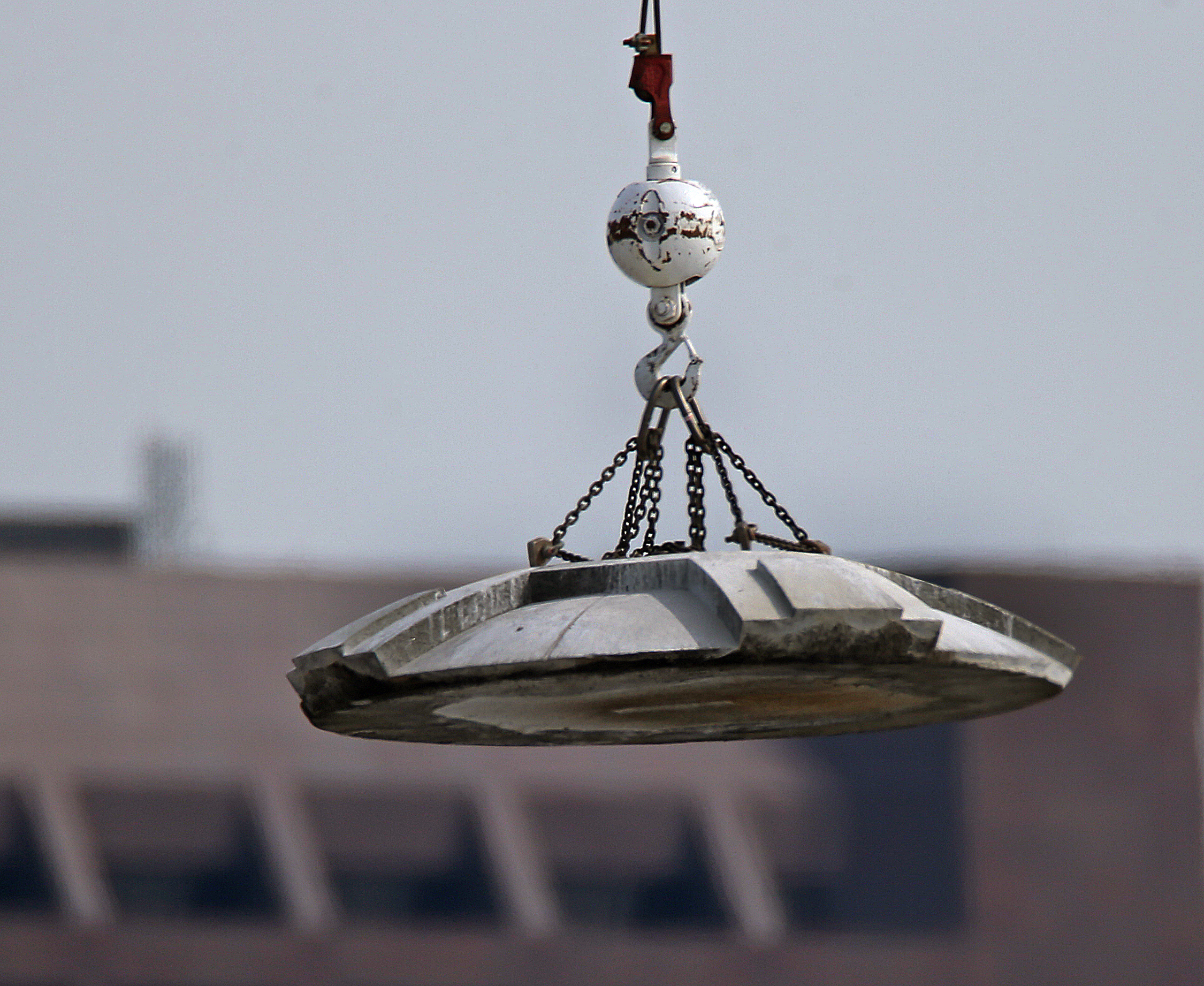 A large mounted crane lifted the cap from the tower.