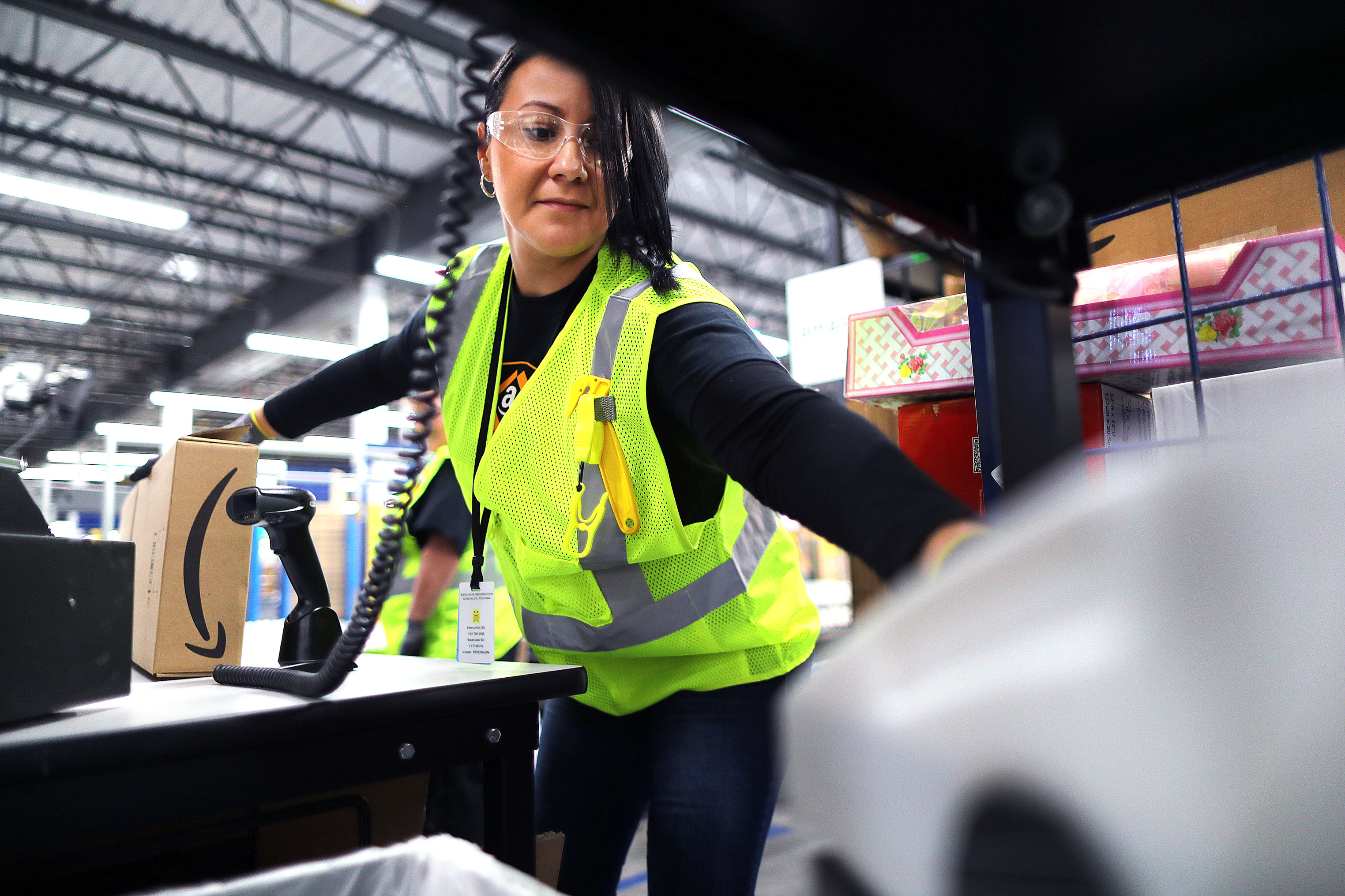 Worker Yesenia Gonzalez reaches for tape to secure a box shut as she processes an order.