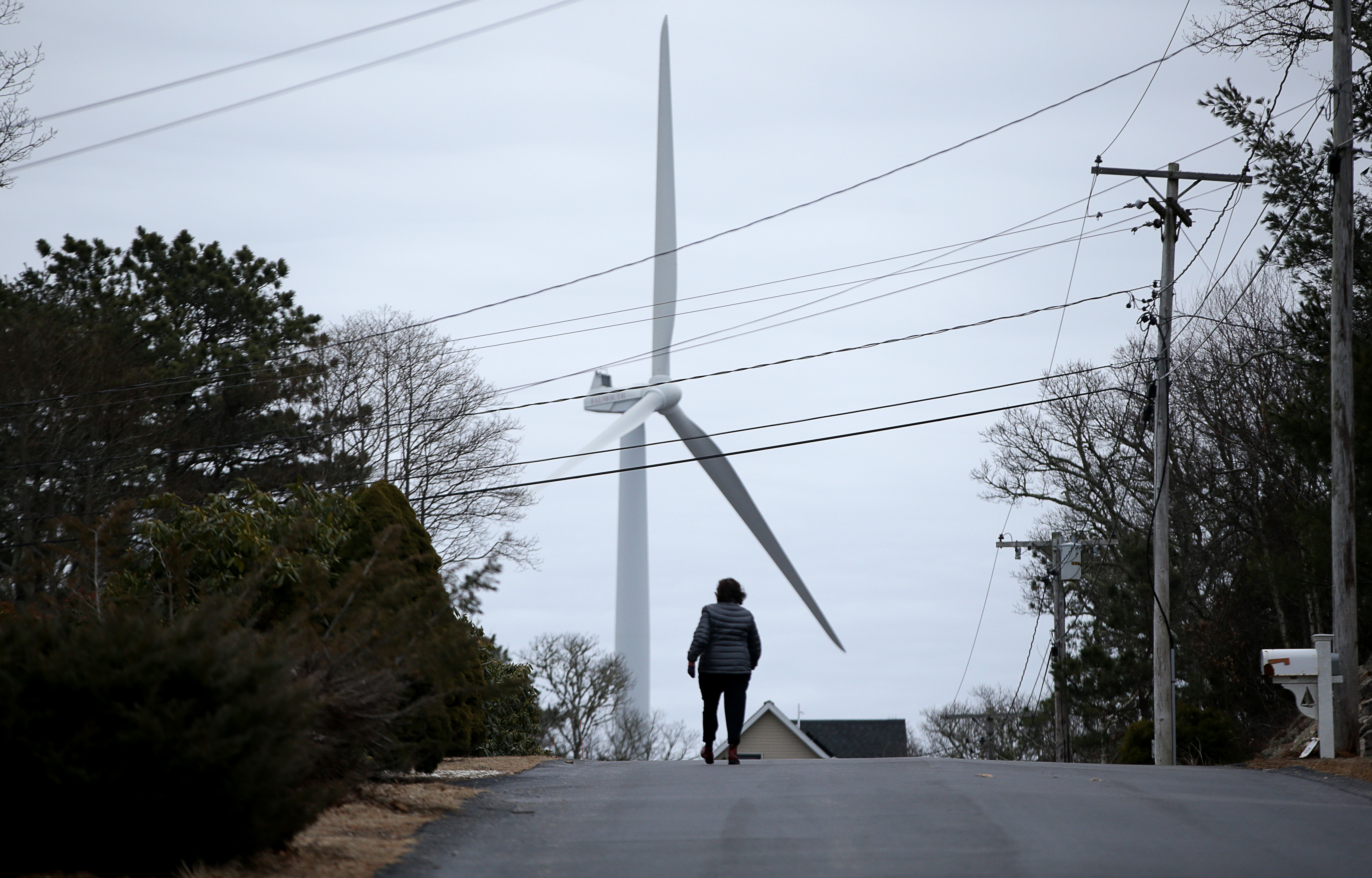A woman walked along Westmoreland Drive in Falmouth, in the shadow of one of the city’s wind turbines.