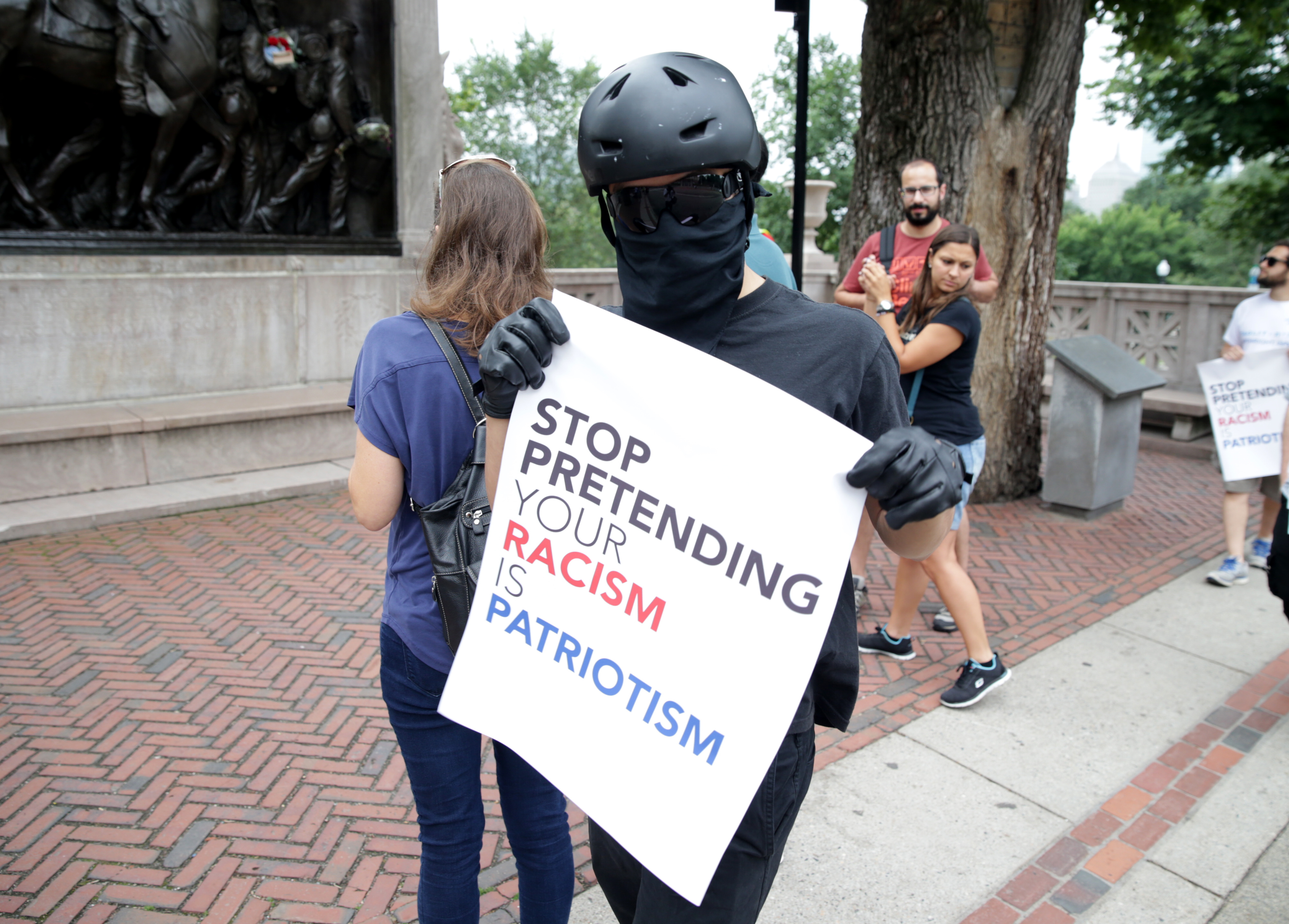 A protester with a bandana and helmet held up a sign.