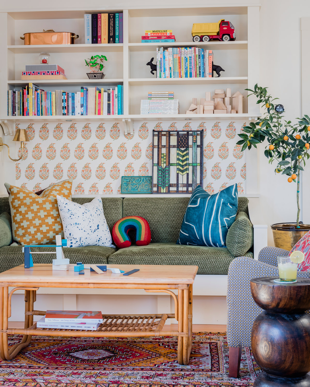 The banquette in the kitchen sitting area has custom chenille cushions. The paisley wallpaper is by Schumacher, and the vintage rattan coffee table sits atop an Oushak rug from Steven King Decorative Carpets.