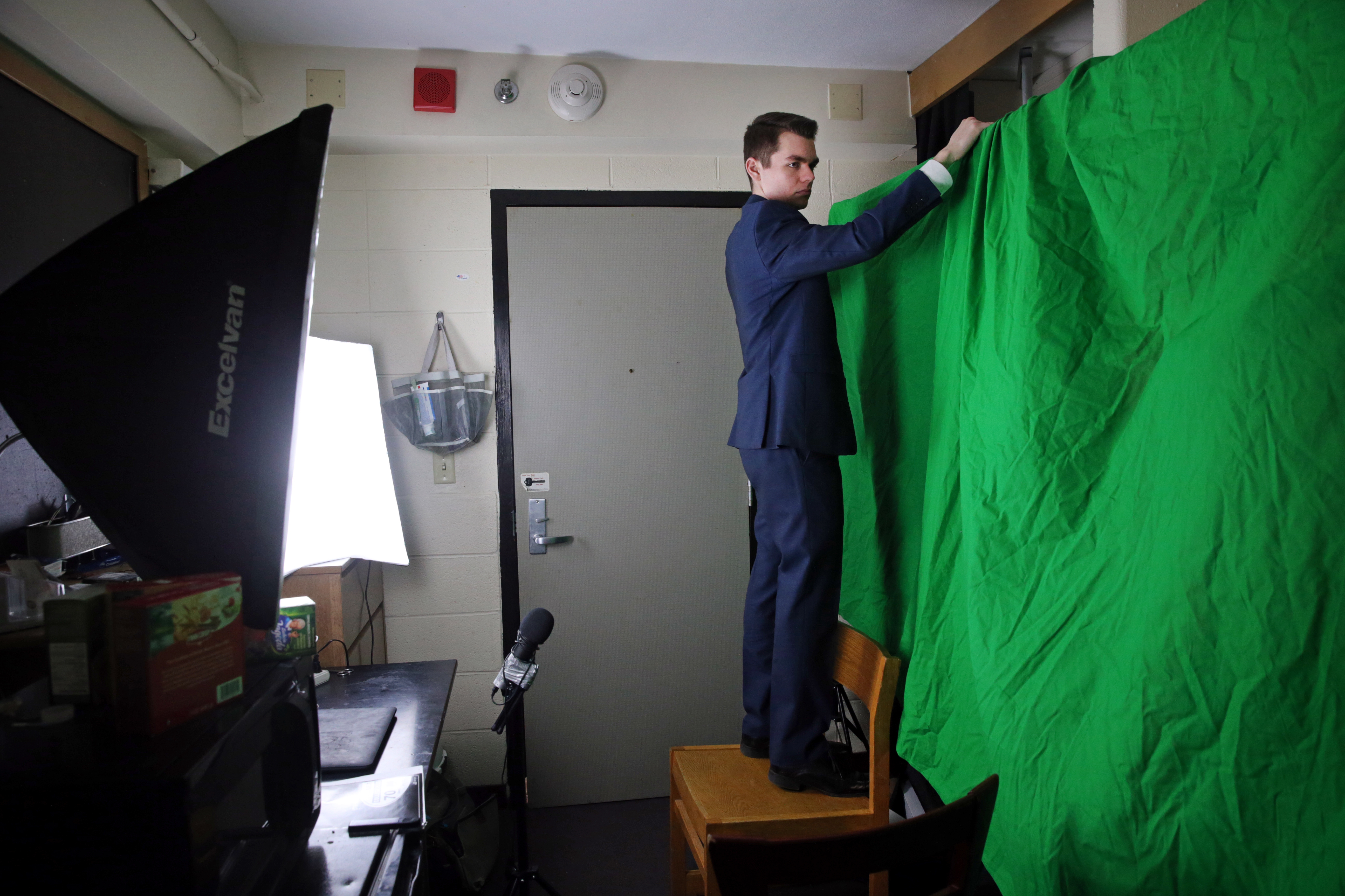 Nicholas Fuentes hung a green screen while preparing to shoot his show in a friend’s dorm room.