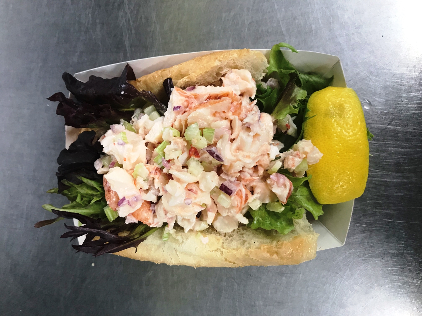 The lobster roll is freshly shucked meat in a light mayo salad with celery and red onion in a lettuce-lined bun.