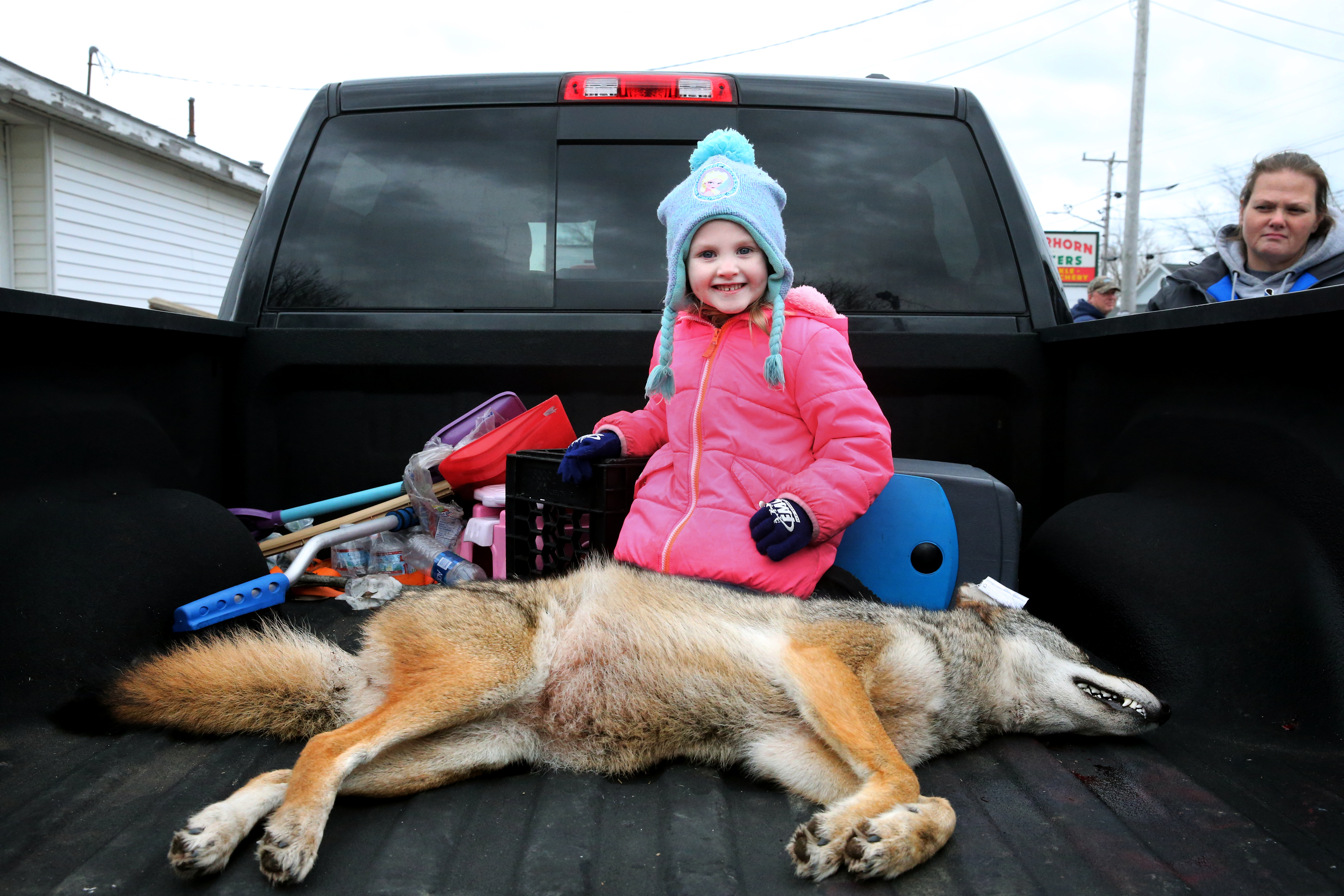 Karla Ropoza (right) of Fall River watched as her daughter, Patience, 4, posed with a dead coyote in the family truck.