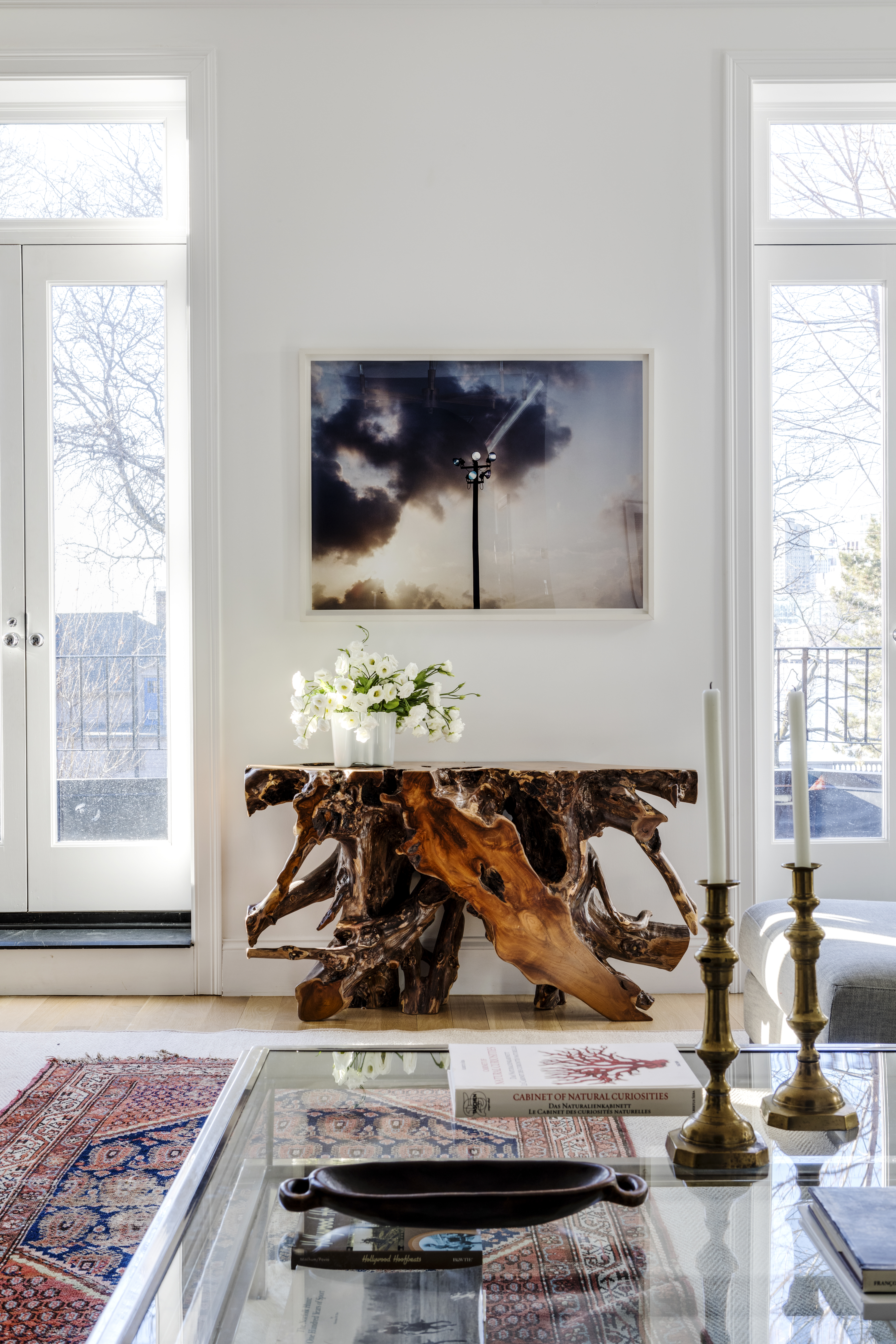 In the living room, a photograph by Charles Cohen hangs over the High Desert Root console table from Wayfair. The vintage Oriental rug warms up the room, painted Benjamin Moore Chantilly Lace.