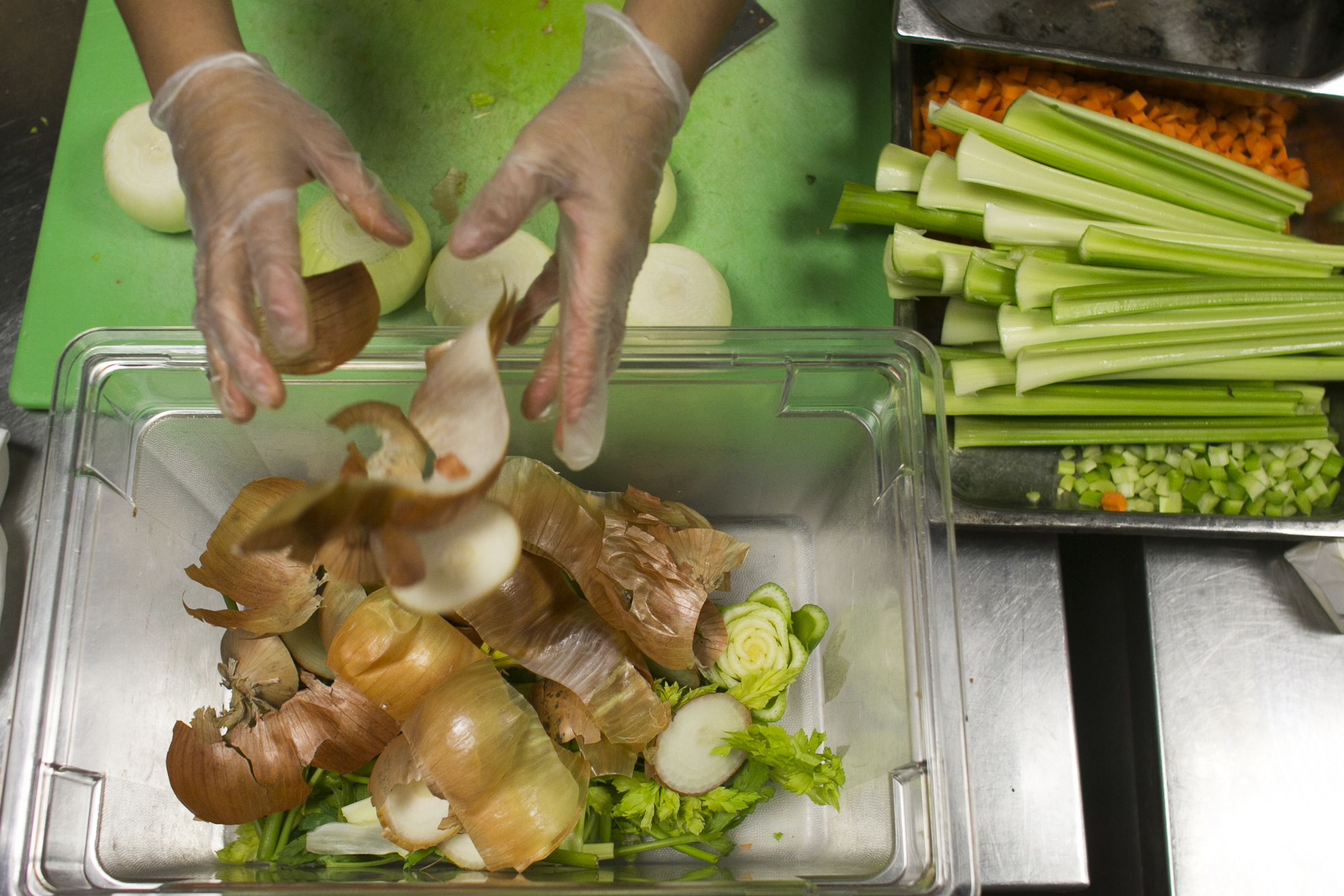 Martinez preps onions in the kitchen and places all compostable waste in a plastic tub.