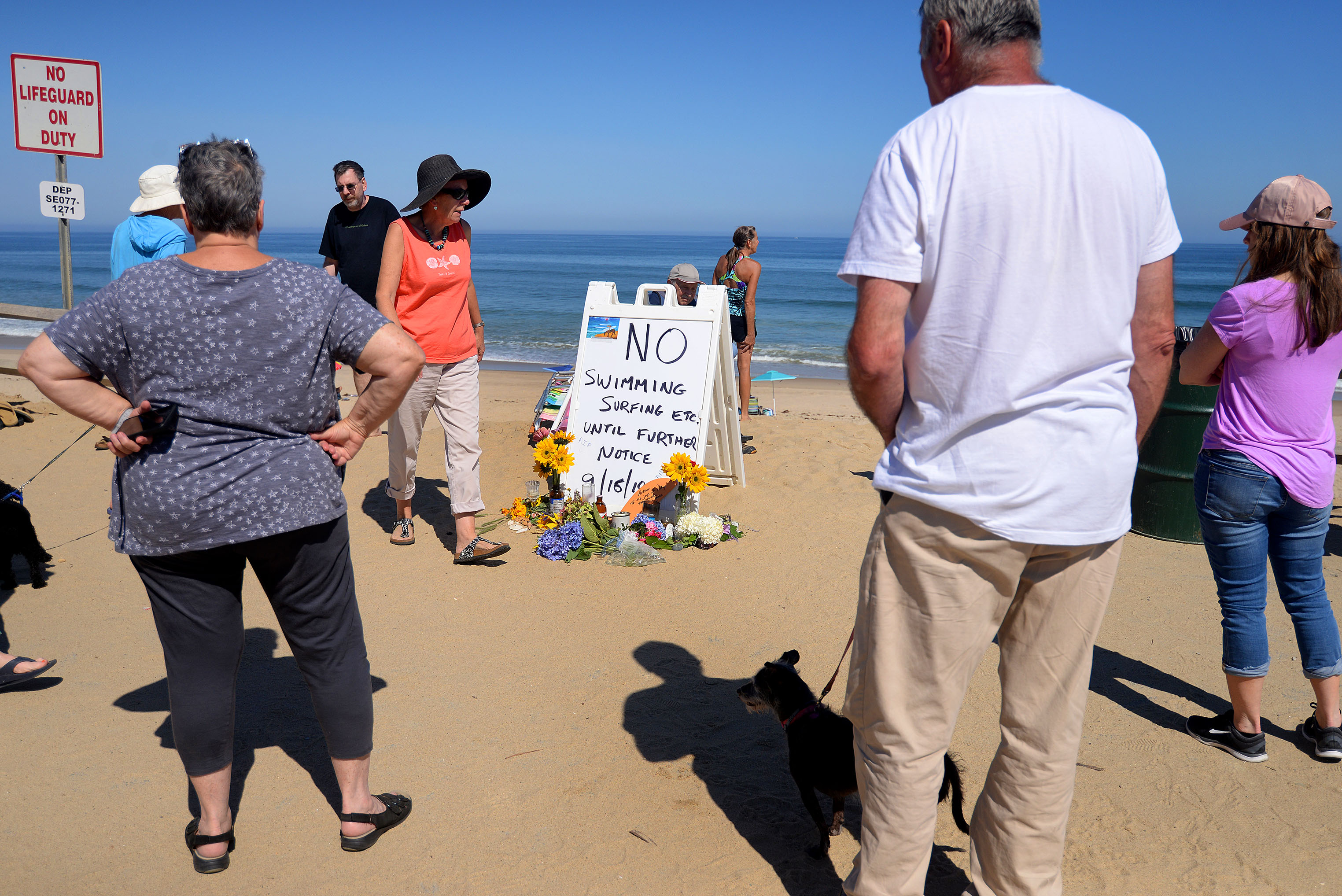 People paused near a make-shift memorial on Newcomb Hollow Beach in Wellfleet for shark attack victim Arthur Medici, who was killed by a shark Saturday while boogie boarding.