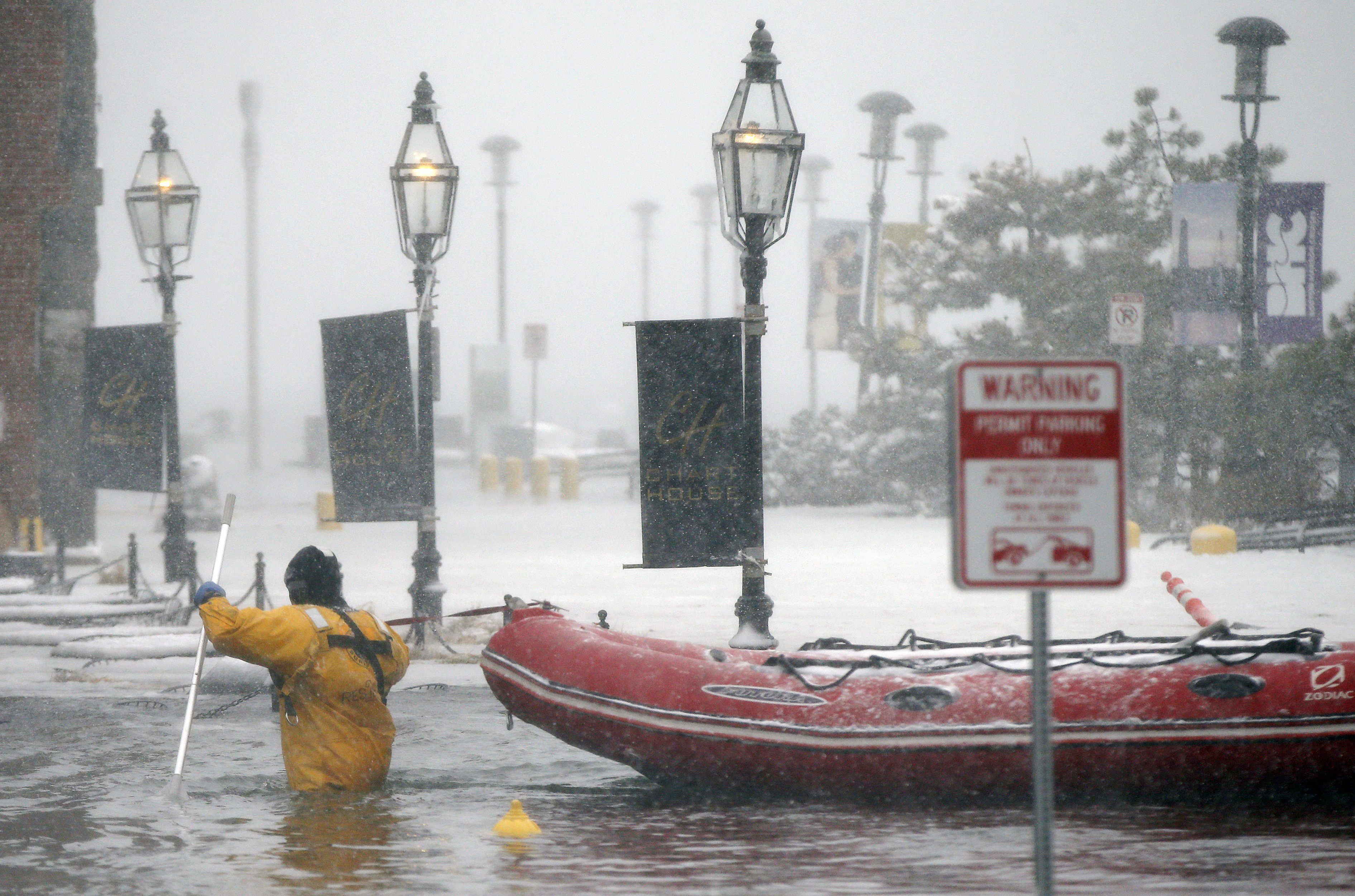 A Boston firefighter waded through floodwaters from Boston Harbor on Long Wharf in Boston on Thursday.