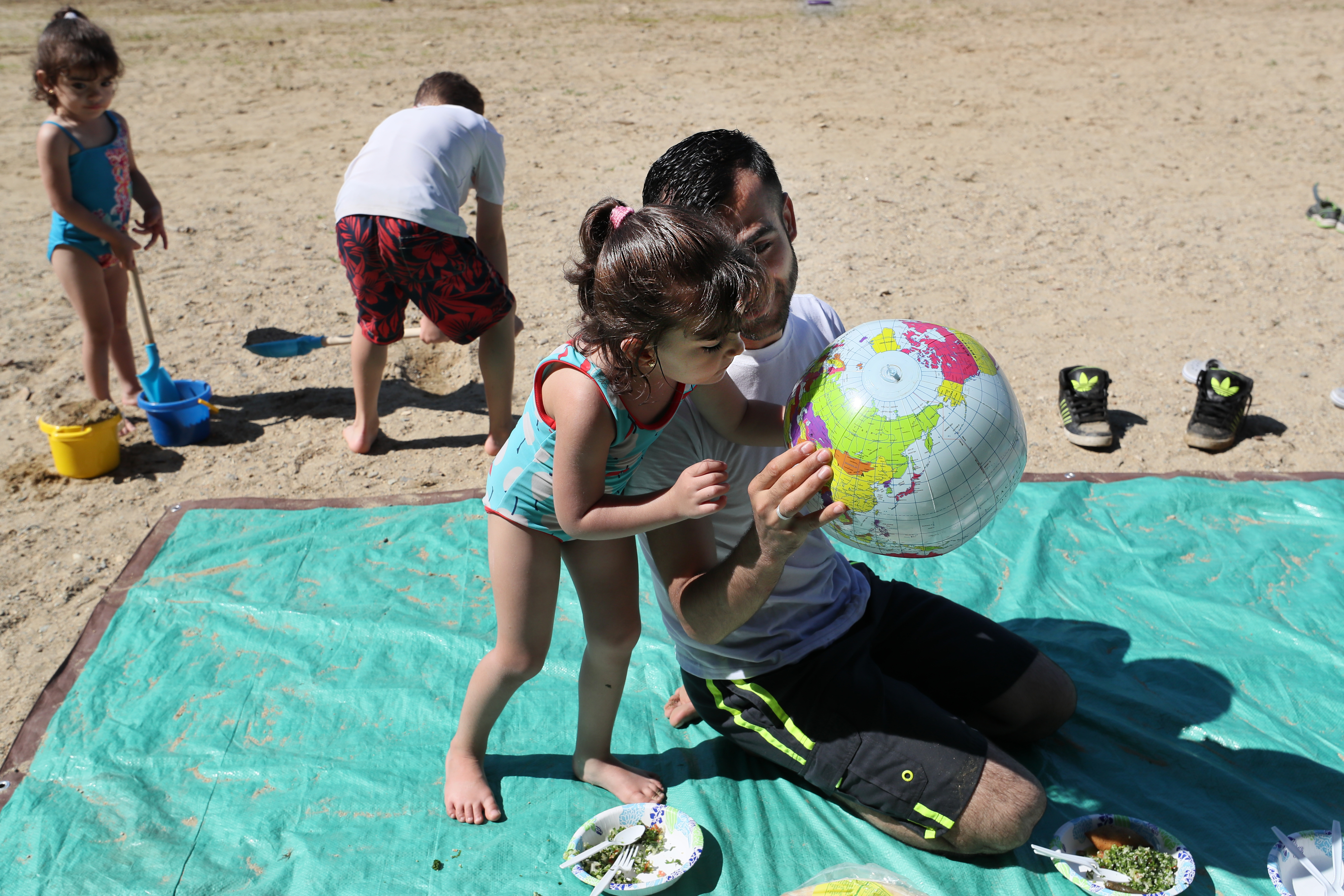 At Walden Pond, Abdulkader held up a beach ball with a map of the world. He showed his daughter Fatimah where Syria was, and told her to kiss it.