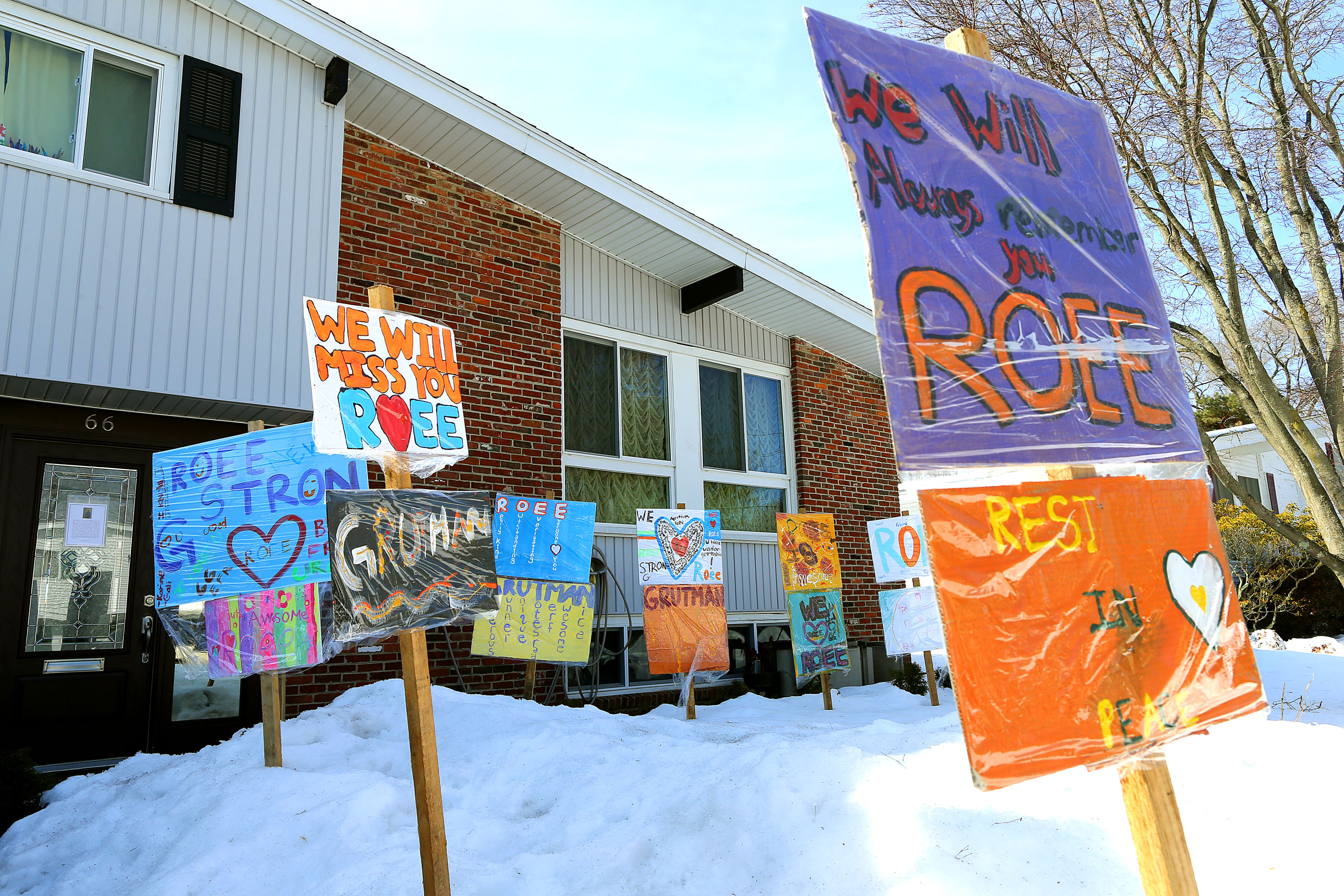 Signs made by children to remember Roee Grutman have been planted in front of the Newton home where he lived.