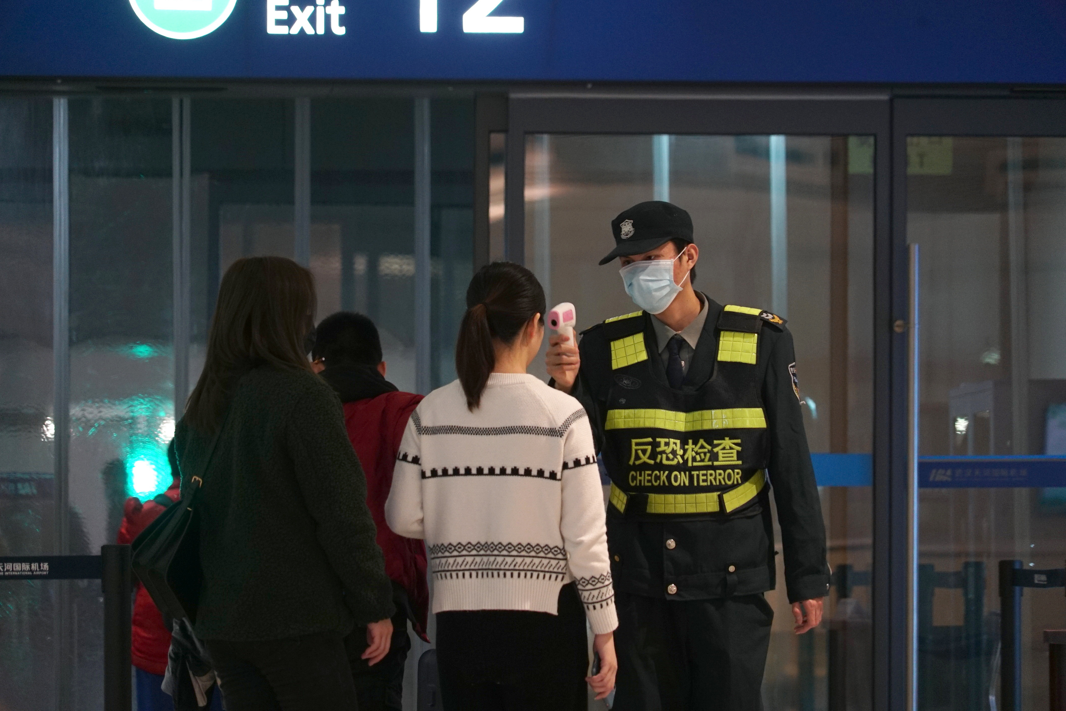 An airport staff member uses a temperature gun to check people leaving Wuhan Tianhe International Airport in Wuhan, China on Jan. 21.