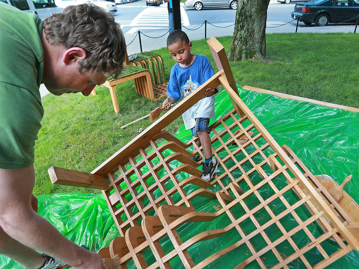 Derek Rieman (left) and 4-year-old Adrias Tanner paints a part of a structure for the parklet being built on a side street near 506 Park Drive.