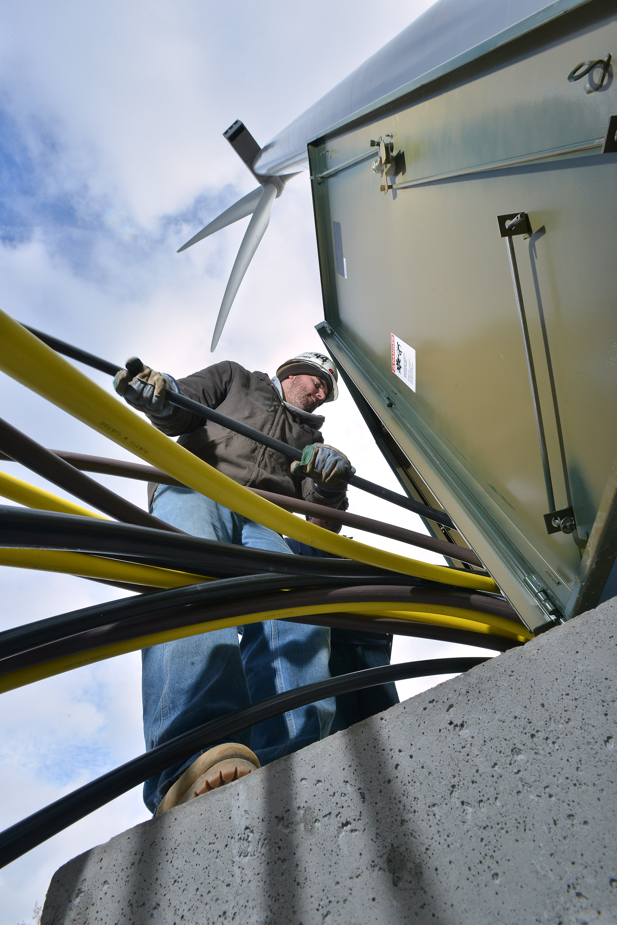 Electricician’s apprentice Brian DiCaienzo works with copper cables at the base of a wind turbine being completed at Varian Semiconductor in the Blackburn Industrial park.