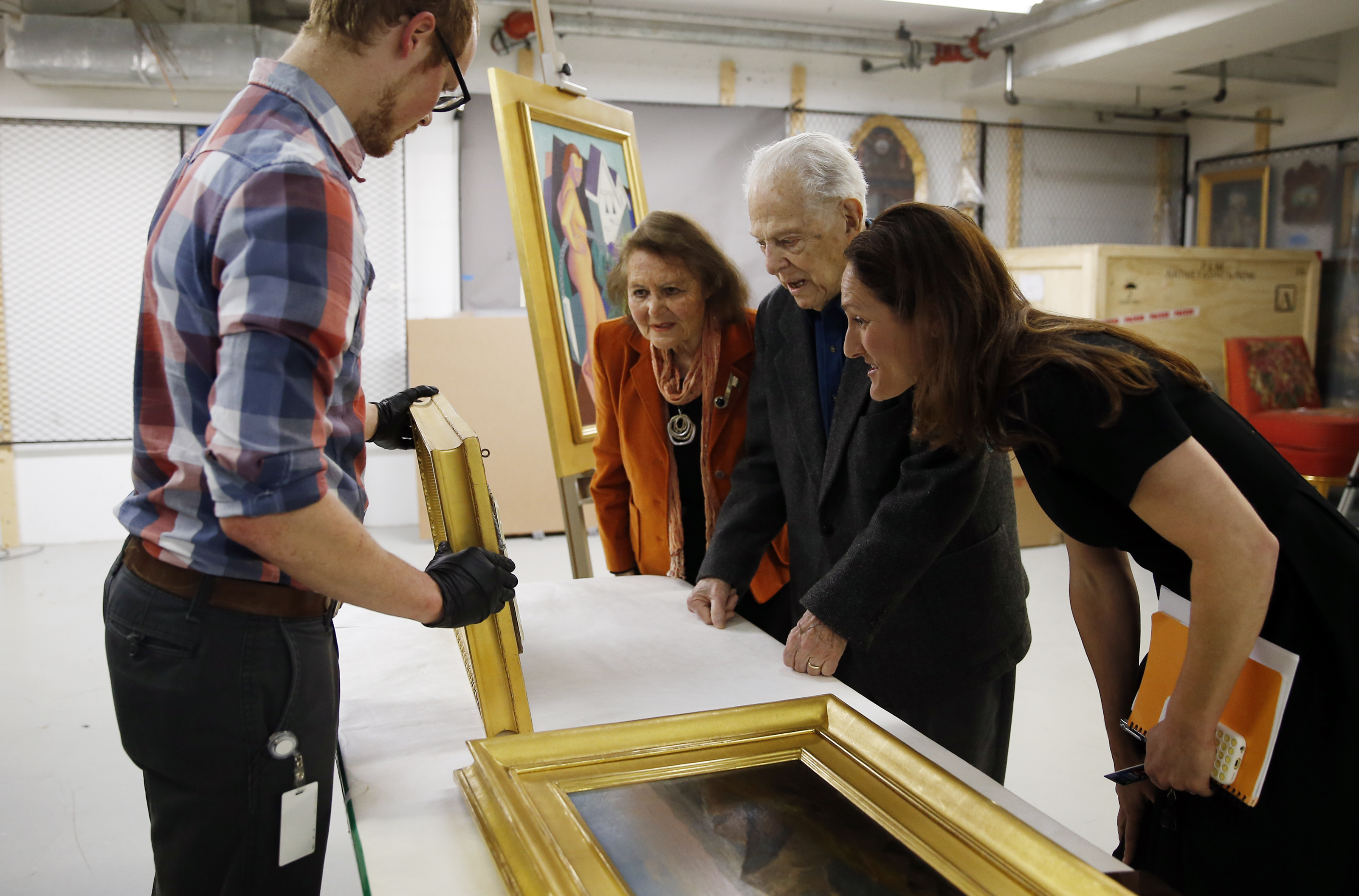 Registrar Adam Brooks held up one of the paintings that Sheila and Sam Robbins donated.