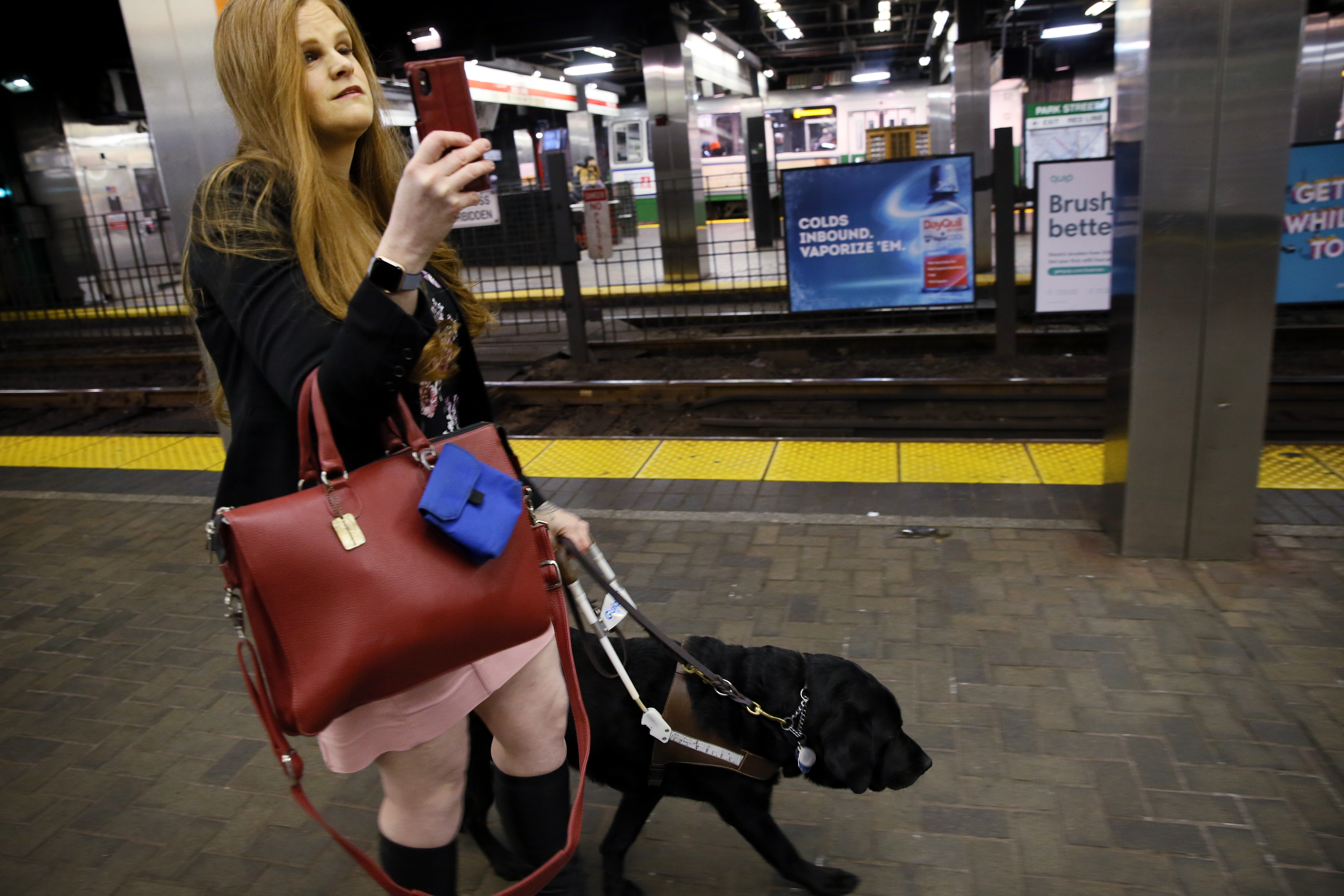 Sassy Outwater-Wright used her smartphone to demonstrate the Aira app while navigating the Park Street T station with her guide dog, Ferdinand.