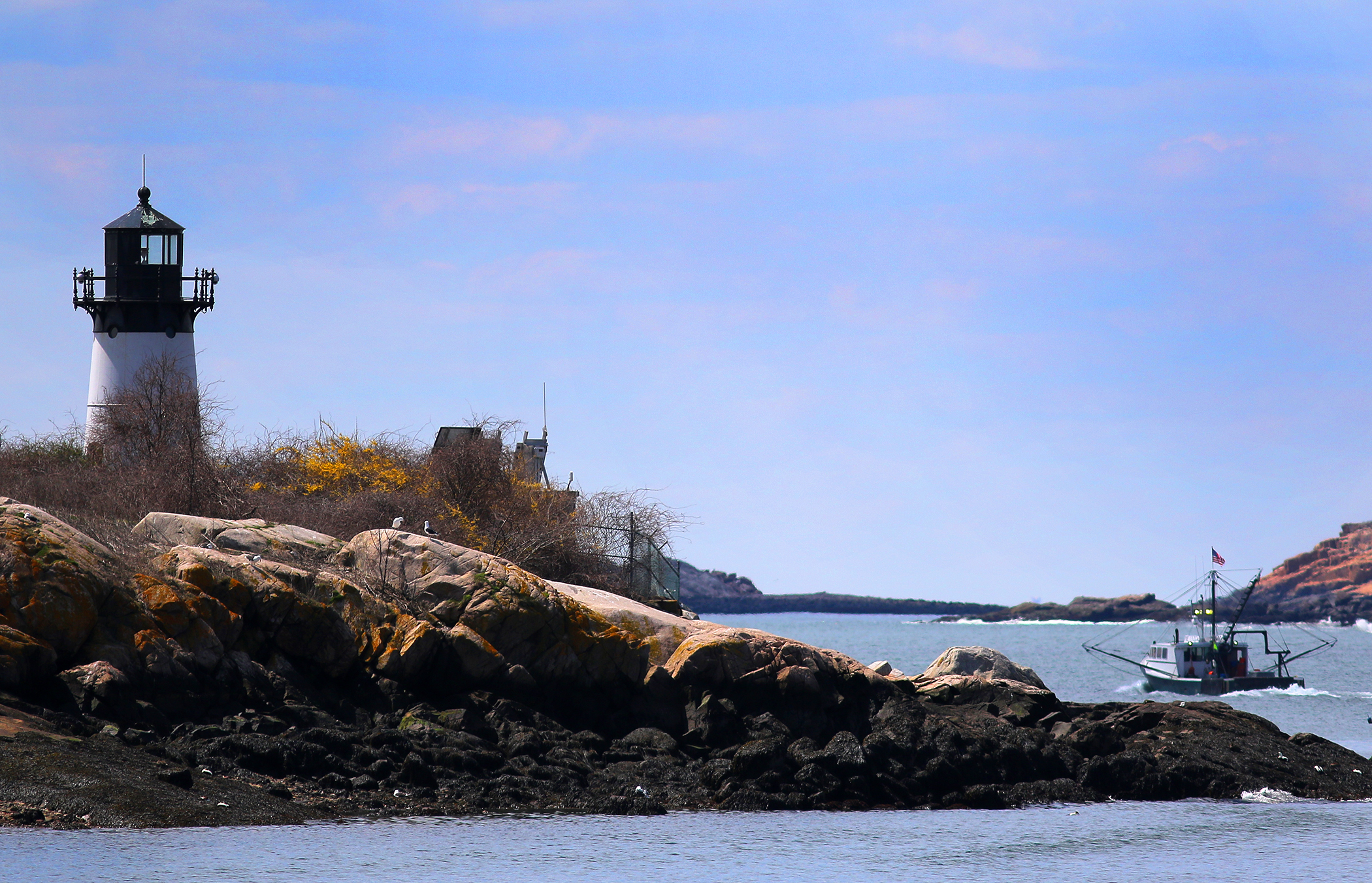 A fishing boat passes Ten Pound Island Lighthouse and heads to sea.