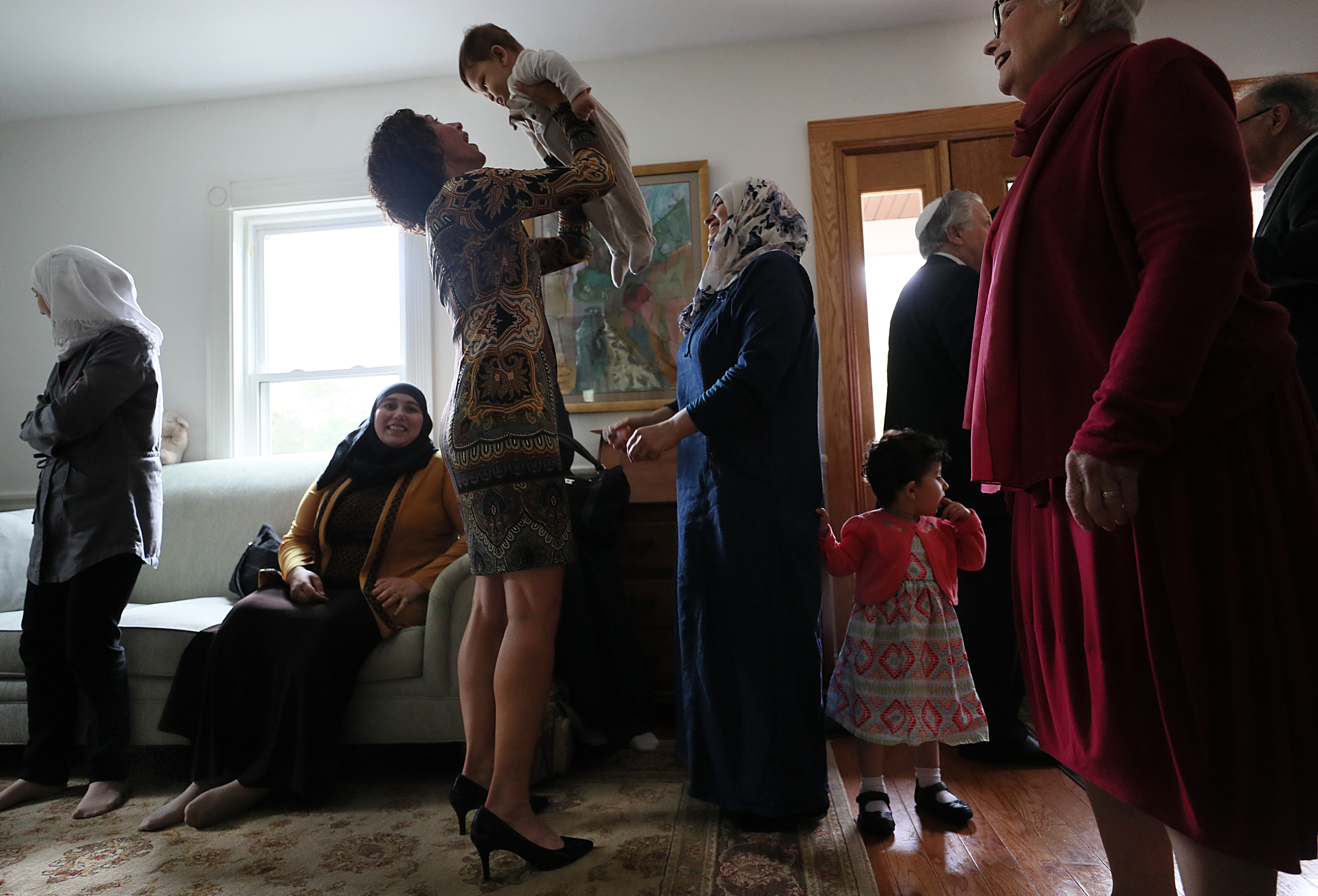 Temple Beth Elohim members mingled with the Syrian families at a party at a temple member’s home. Barbara Shapiro, one of the Jewish volunteers, picked up the youngest of the Syrian refugees.