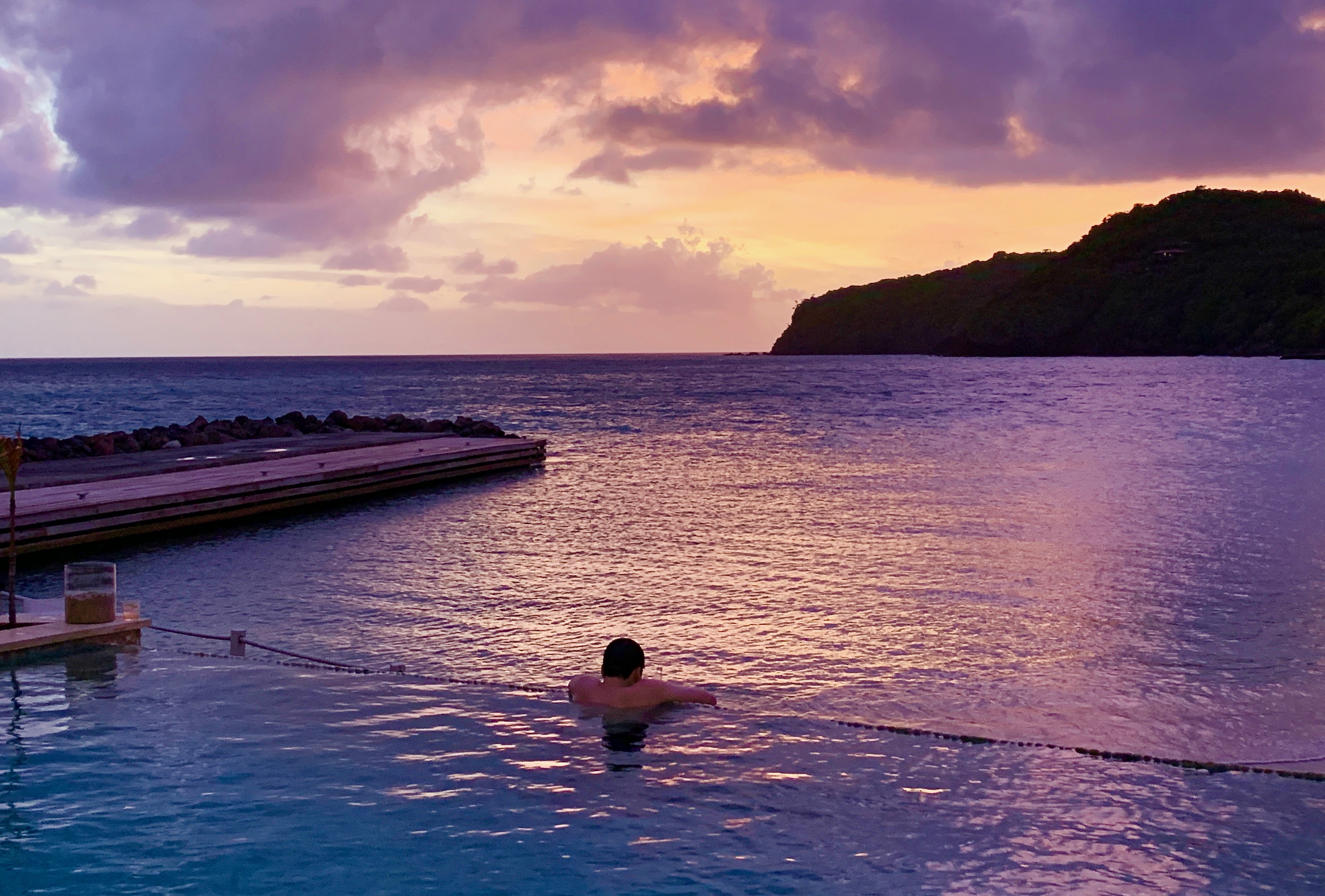 A guest at the Liming hotel watches the purple glow of the sunset from an infinity pool.