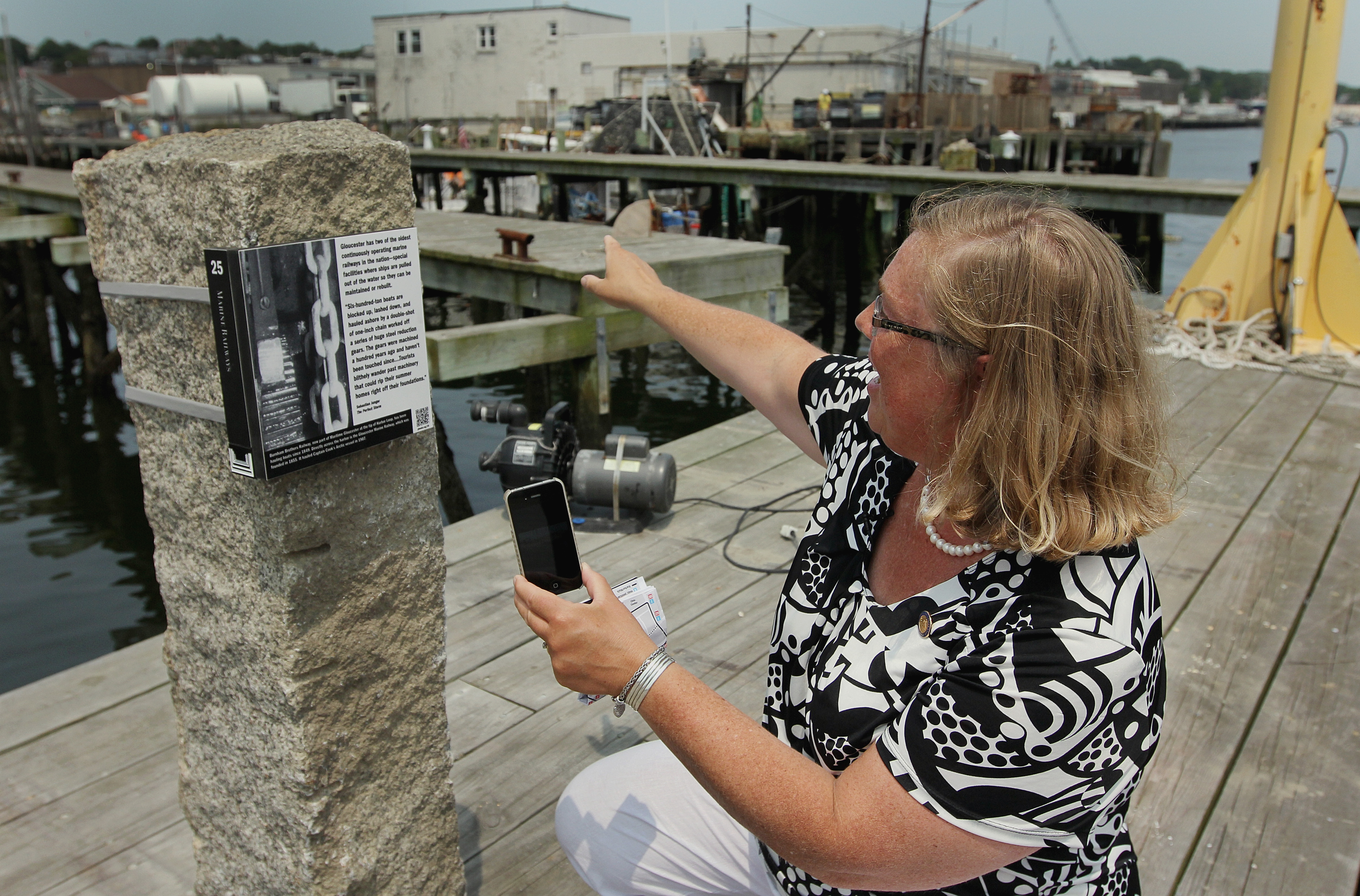 Gloucester Mayor Carolyn Kirk demonstrates how QR codes enable an interactive smartphoe tour along the city’s HarborWalk.