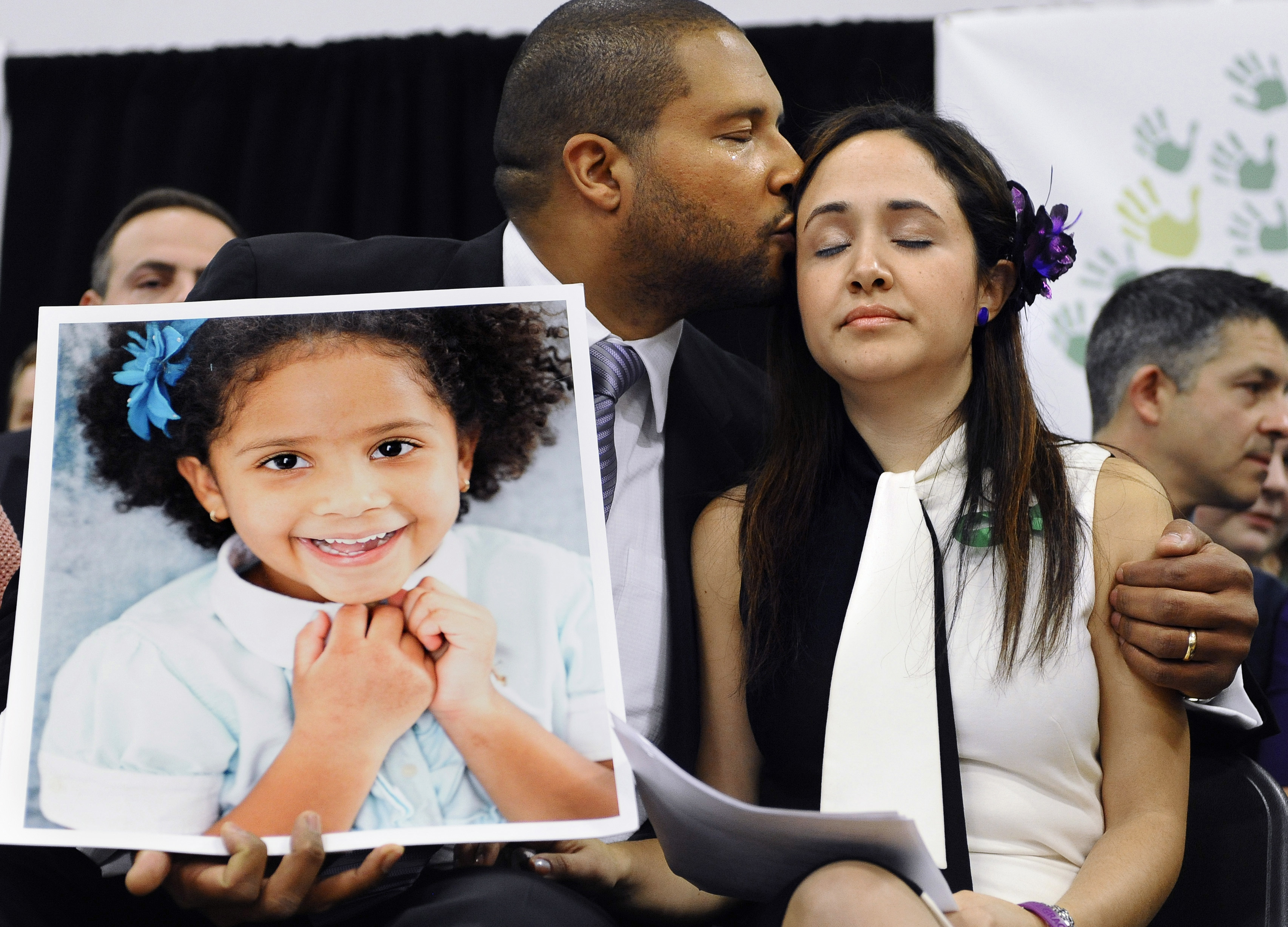 Jimmy Greene, left, kissed his wife Nelba Marquez-Greene while holding a portrait of their daughter Ana.