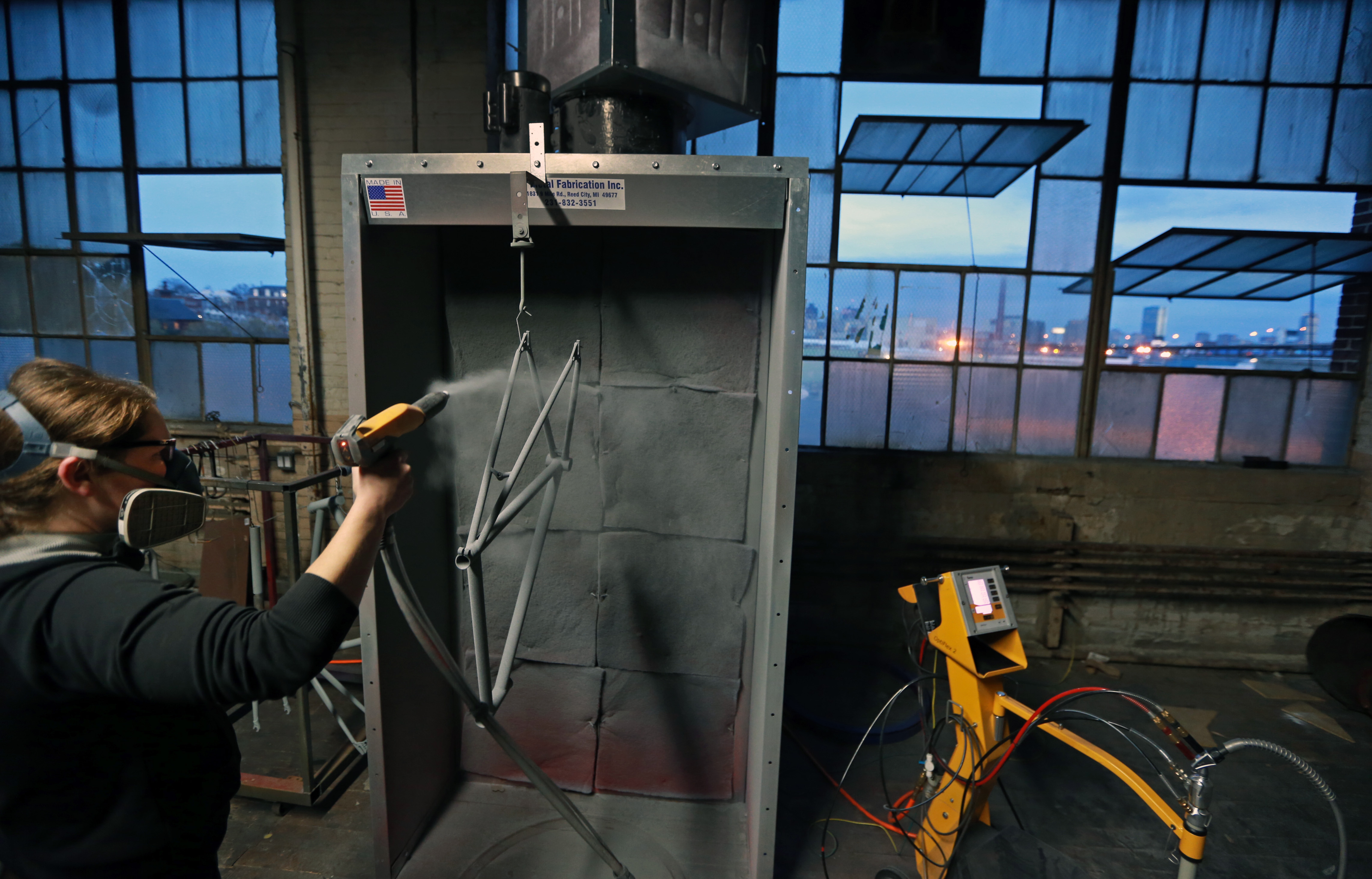 With the Boston skyline visible out the windows of her Charlestown business, Hub Powderworks, Thibodeau coated a bicycle frame.