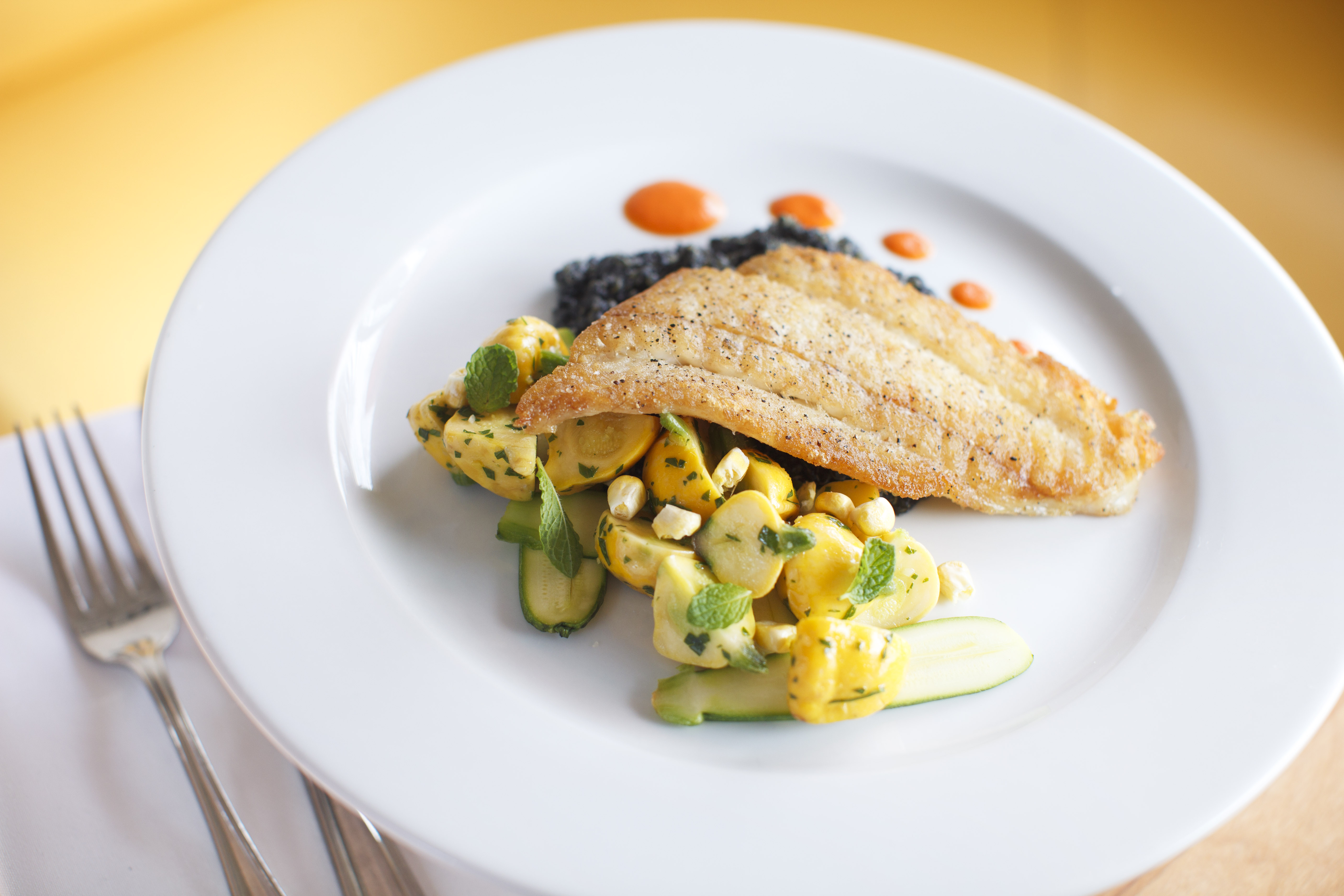 Rhode Island Fluke, on a bed of black squid ink quinoa, served with green and yellow squash and mint.