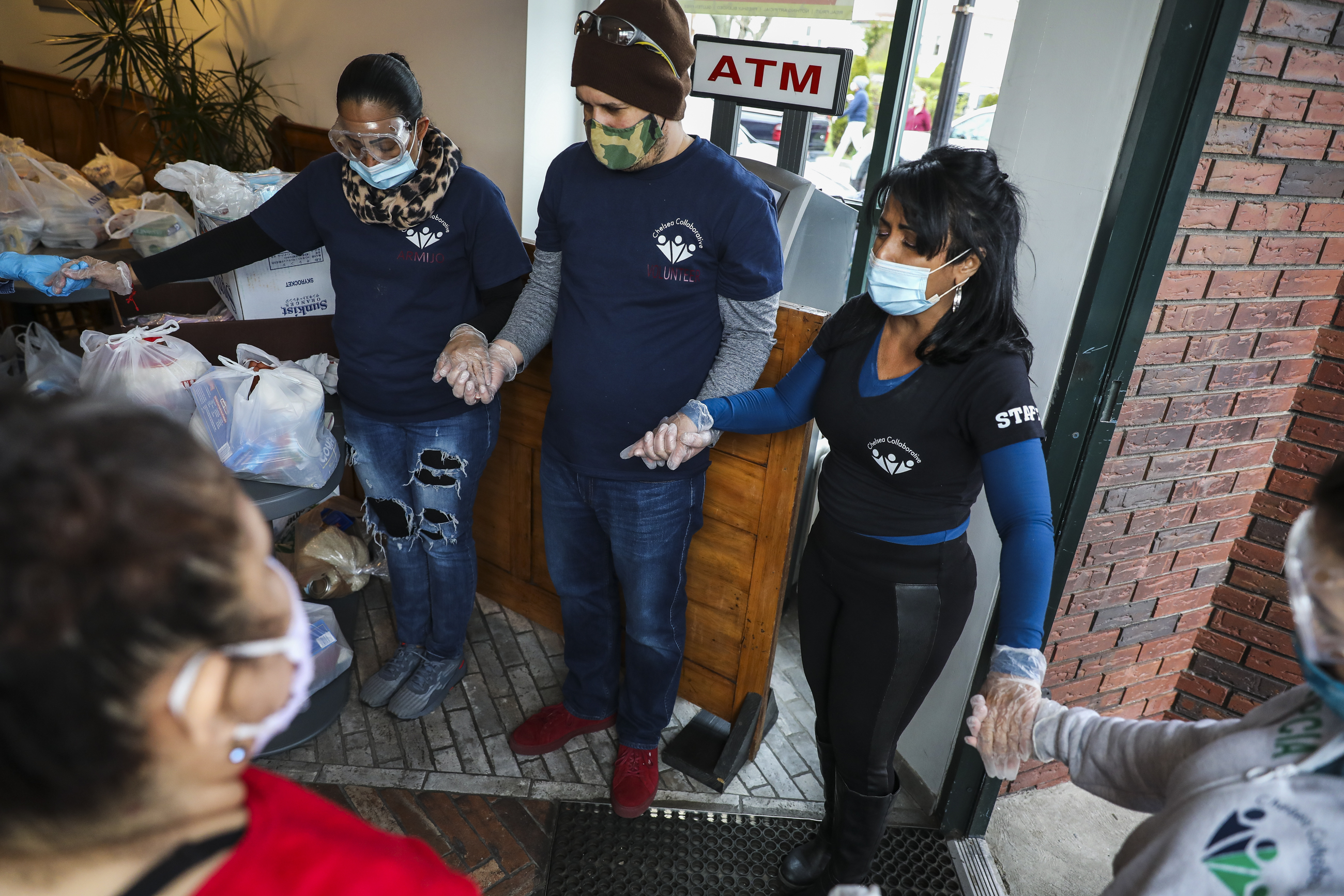 Gladys Vega, right, executive director of Chelsea Collaborative, lead a prayer before opening the doors to a pop-up food pantry.
