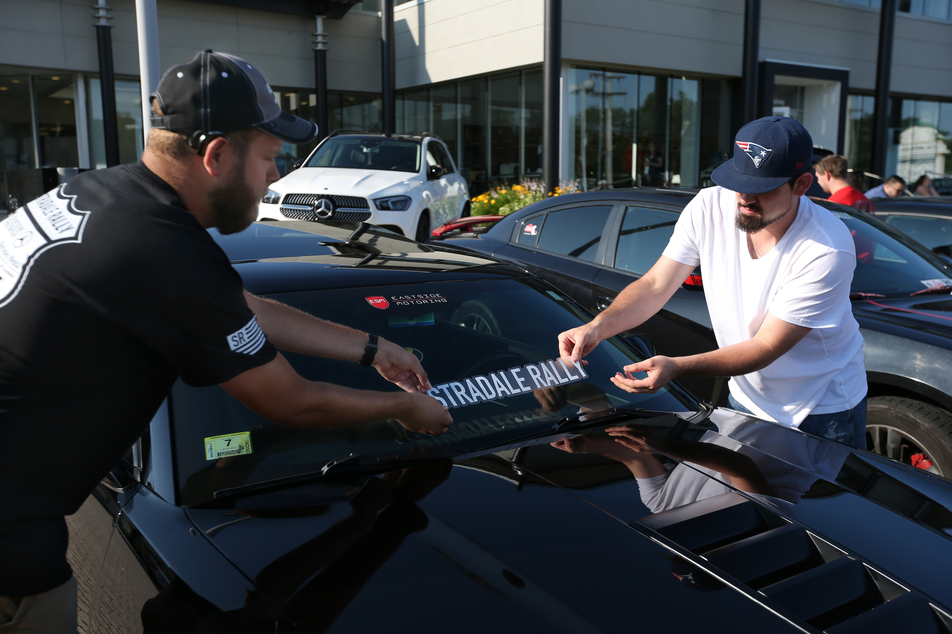 Brandon Bailey (left) and Timothy Irvin placed a decal on a car during the Stradale Rally at Flagship Motorcars of Lynnfield in Lynnfield.