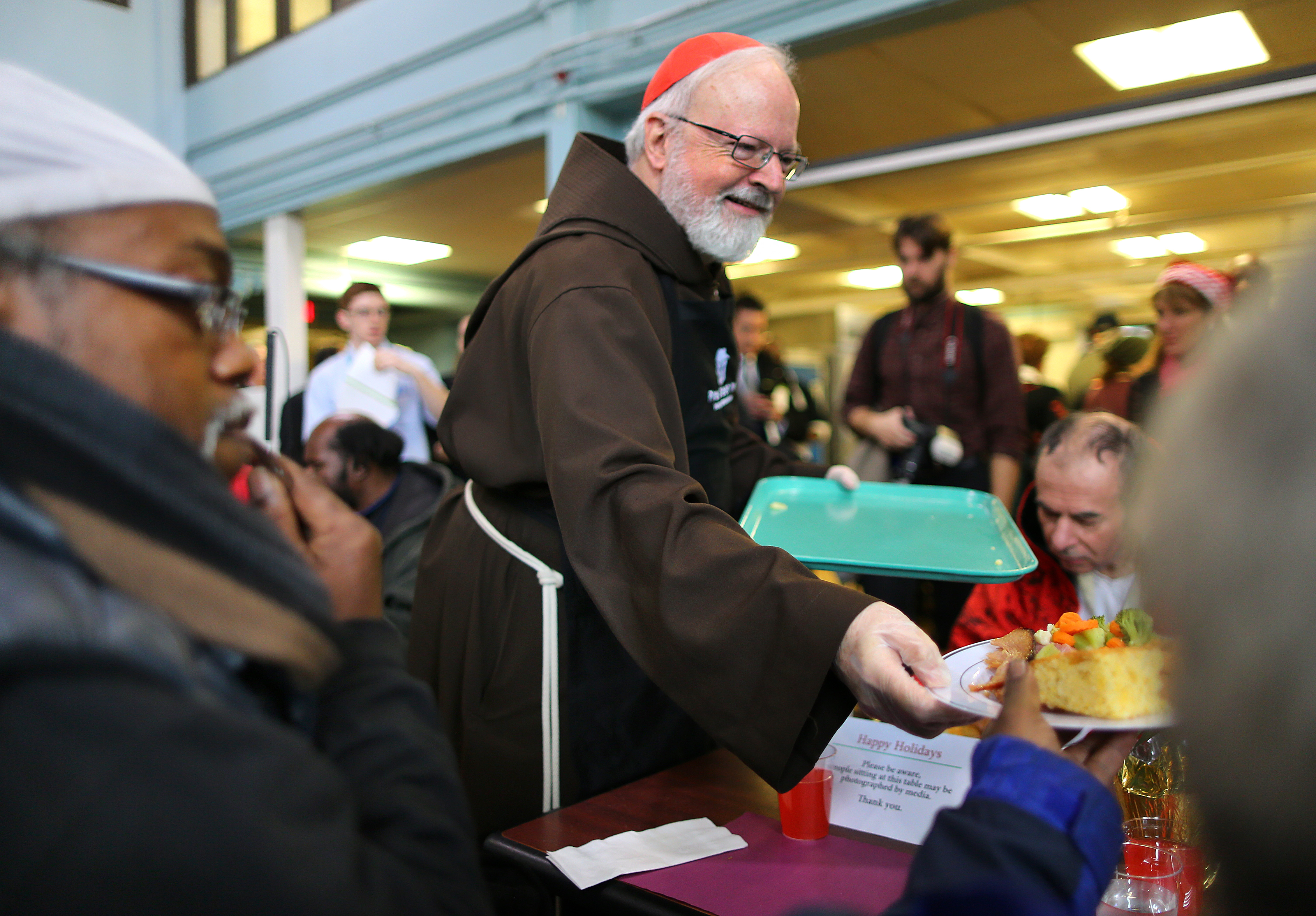 Cardinal Sean P. O'Malley said a prayer and then served a plate at the Christmas Eve luncheon.