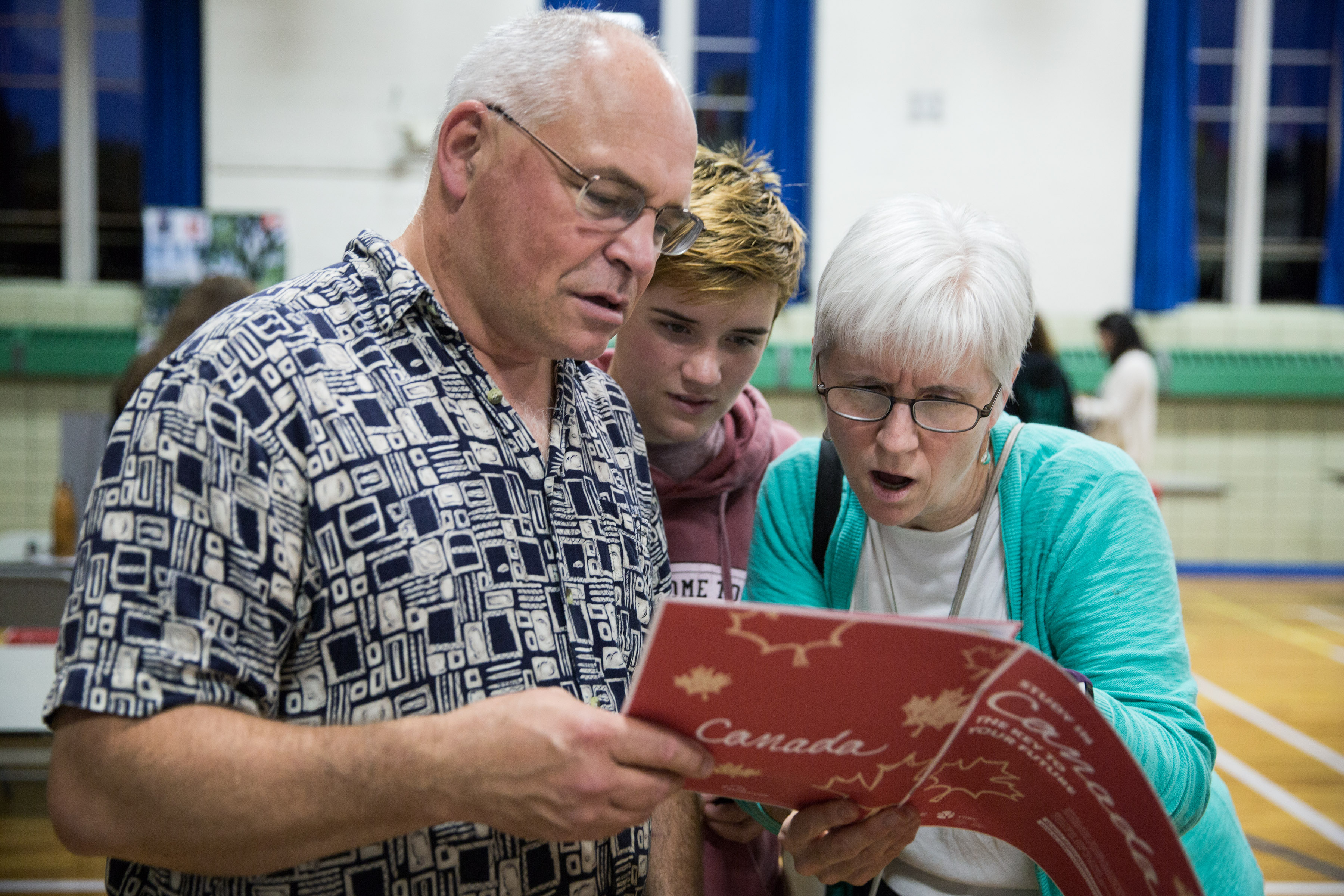 From left to right: Dan Taylor, Rebecca Taylor, 16, and Joan Smith, examined a EduCanada booklet at the EduCanada fair held at the International School of Boston.