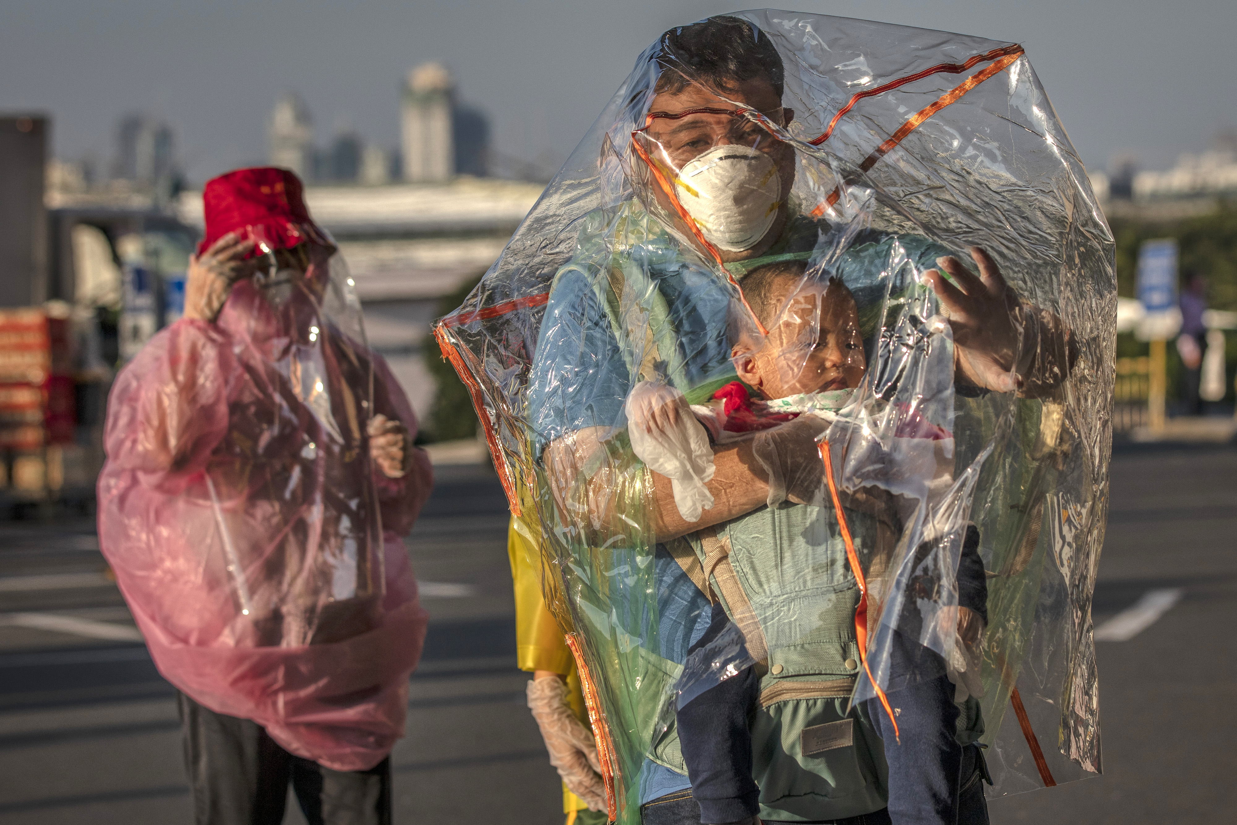 Travelers wore raincoats, plastic covers, gloves, goggles, and facemasks as they wait for their flight at Ninoy Aquino International Airport on Wednesday in Manila, Philippines.