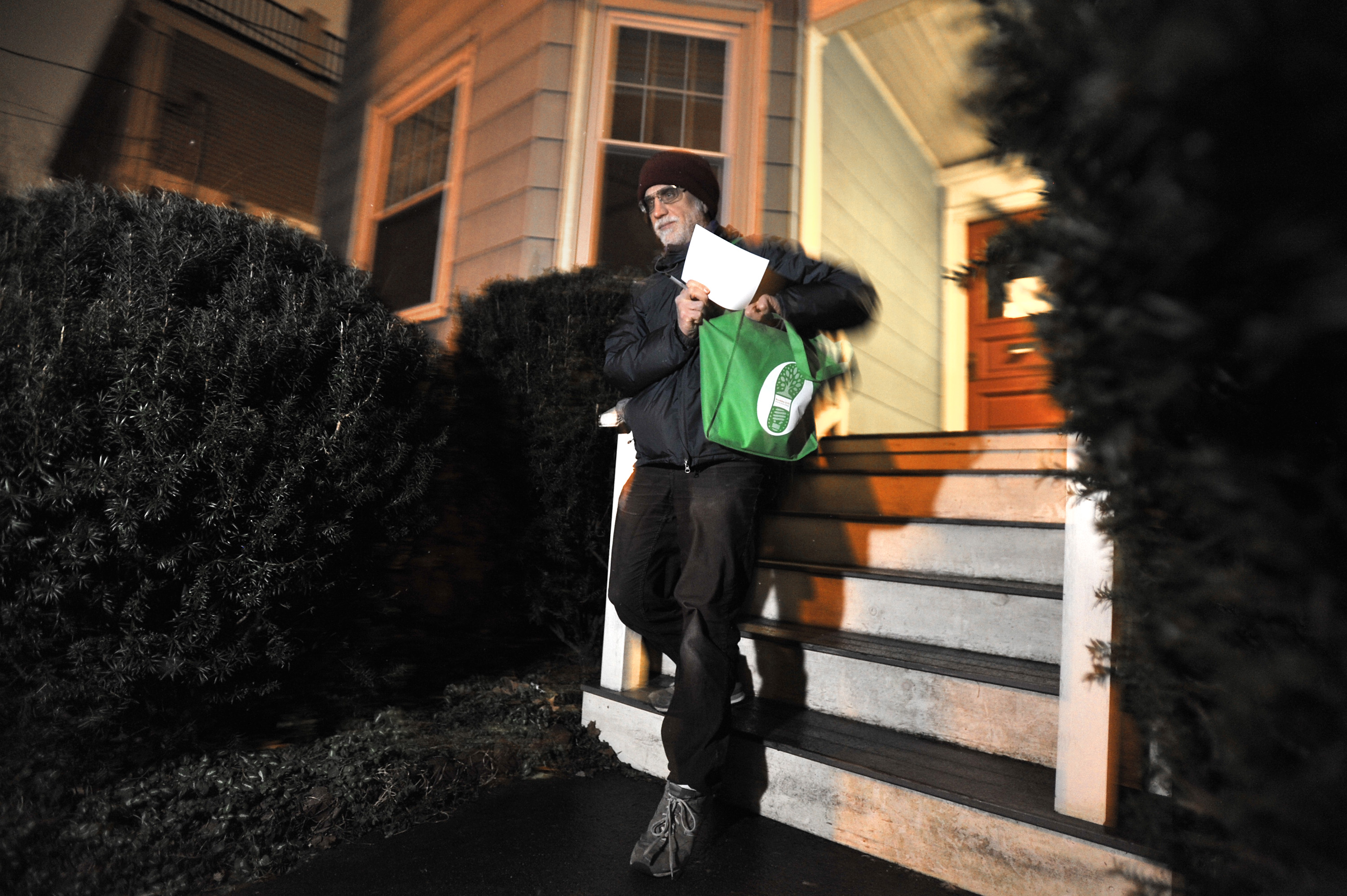 Loechler leaves a house after dropping off brochures explaining renewable energy programs available from utility companies.