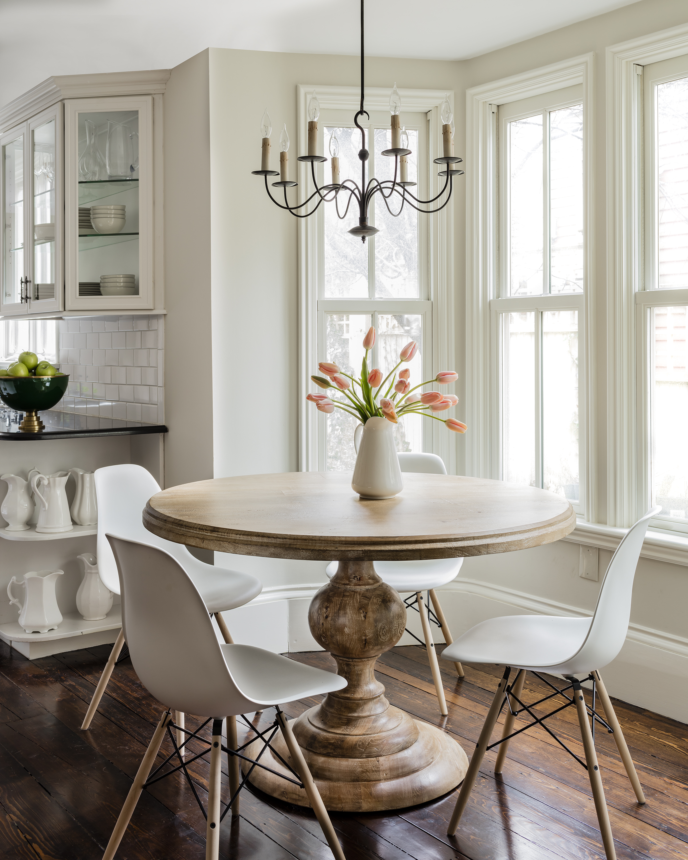 The round kitchen table is from Four Hands. “The pedestal shape is very traditional, while the finish is easy, casual, and approachable,” says Borges. The Herman Miller Eames molded plastic dining chairs are from Design Within Reach. The beautiful old pine floors are original to the house.