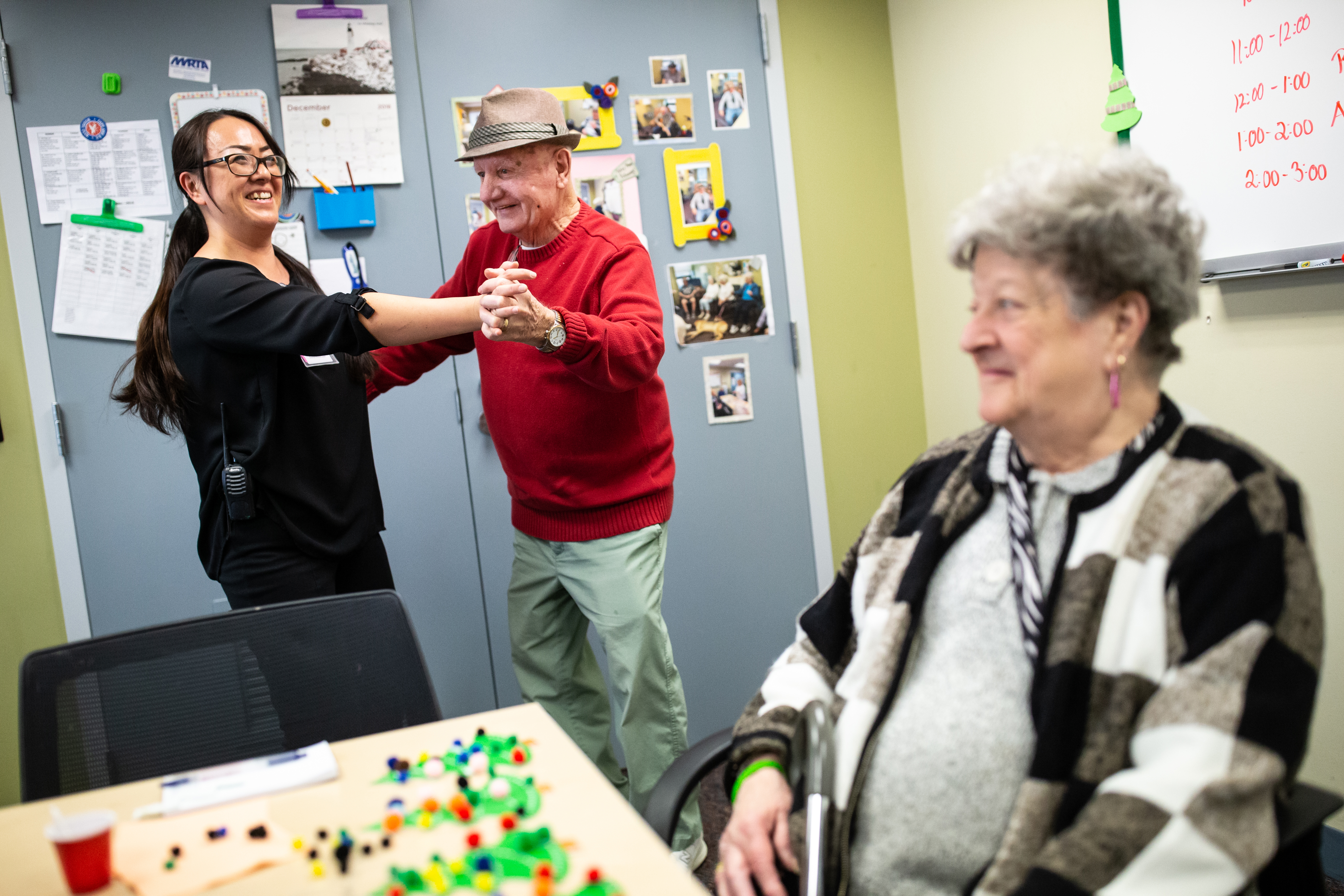Ron St. Jean, 82, shakes off the blues by dancing with activities leader Ayako Tarbell while Sandra Kowalski, 77, makes crafts at the Amesbury Senior Community Center.