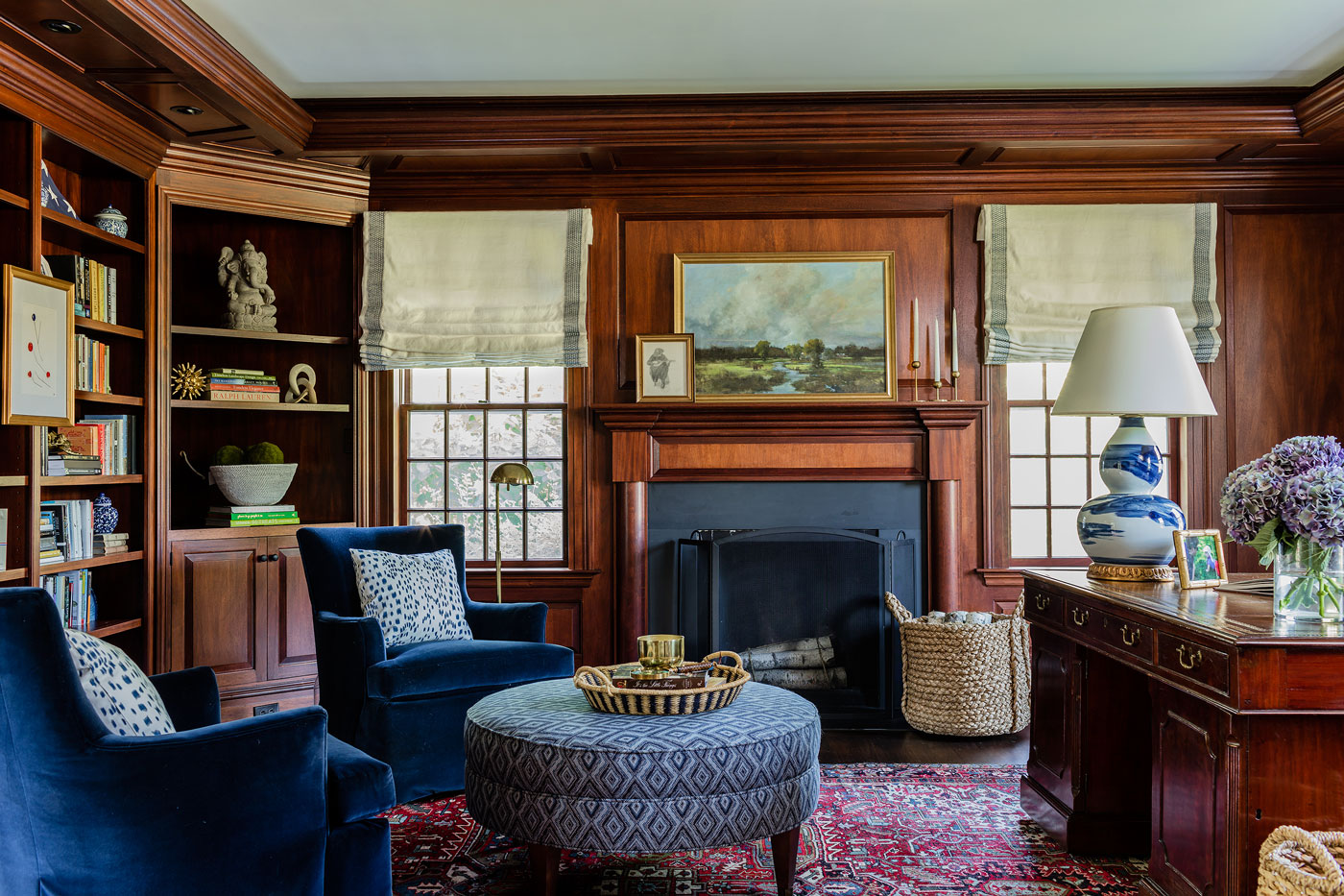 A landscape painting by Bethanne Cople, from Huff Harrington in Atlanta, hangs above the fireplace in the study, and a ceramic lamp with a brushstroke pattern by Bunny Williams Home brightens the desk.