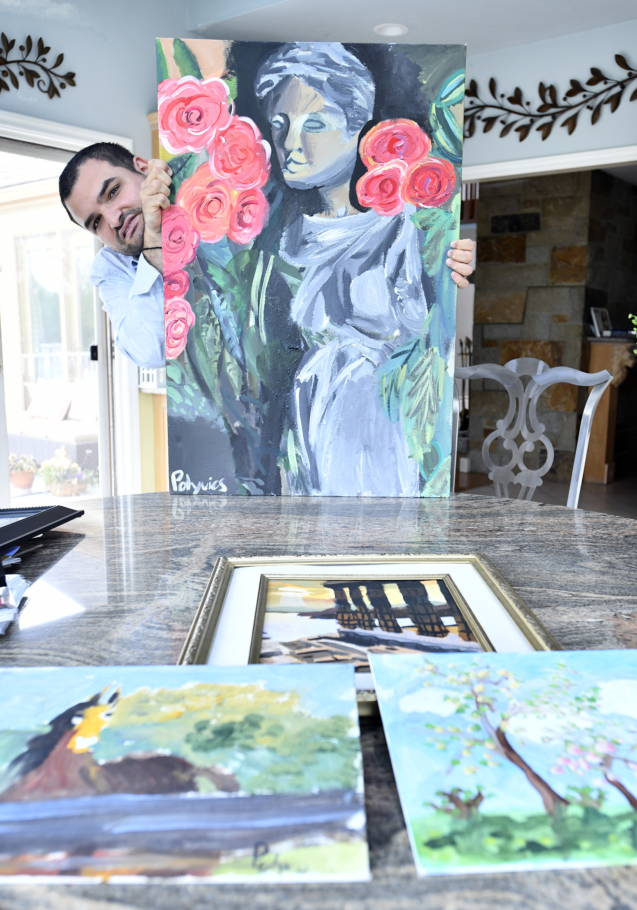 Polyvois Christoforos holds a painting he created of a Greek statue.