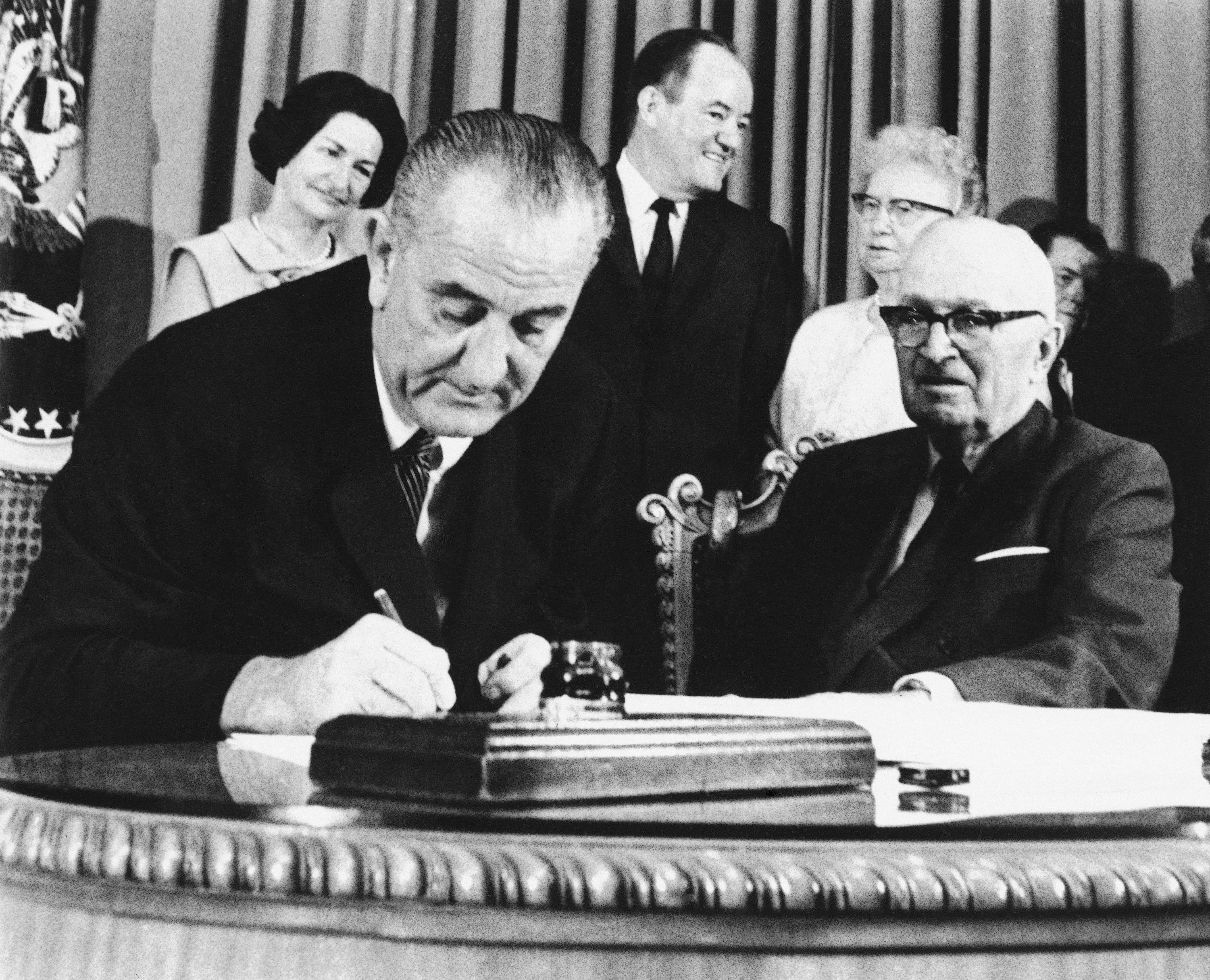 President Lyndon Johnson signed the Medicare Bill into law on July 30, 1965 while former President Harry S. Truman looked on.