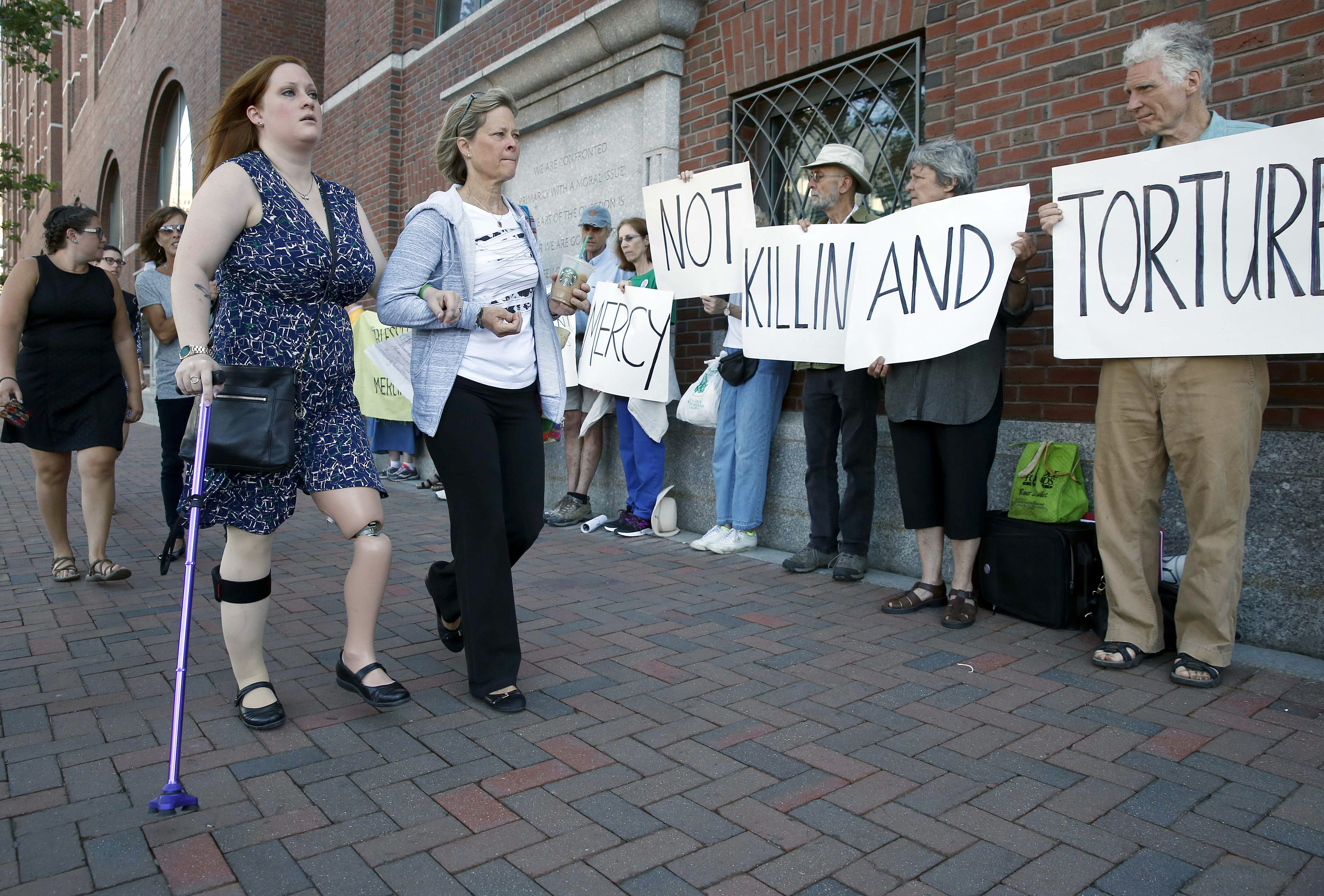 Bombing victim Erika Brannock, left, and her mother Carol Downing walked past demonstrators outside the courthouse.