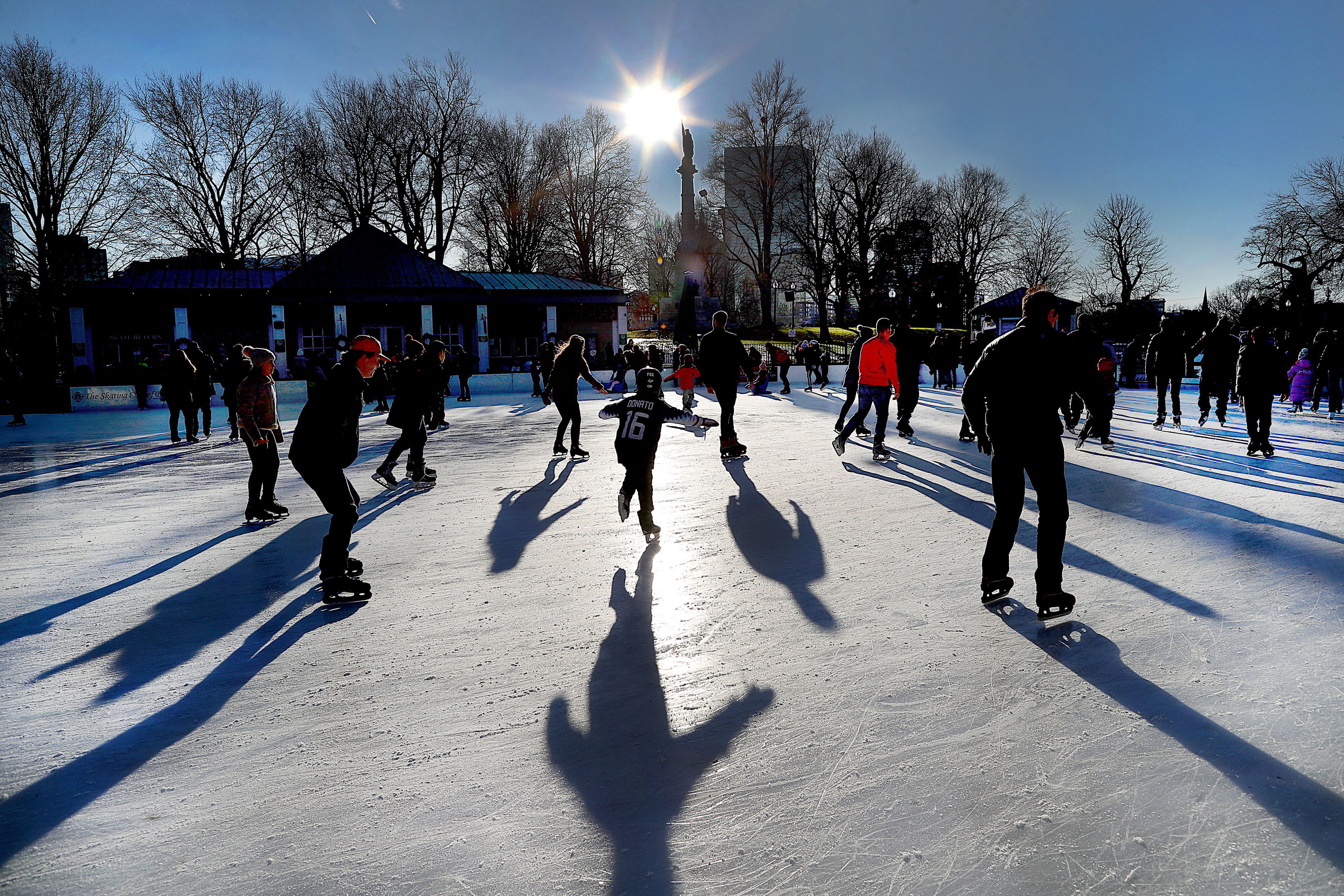 Skaters cast long shadows as they enjoyed a fairly warm Christmas Eve skating under a brilliant sun on the Boston Common Frog Pond skating rink on Dec. 24, 2019.