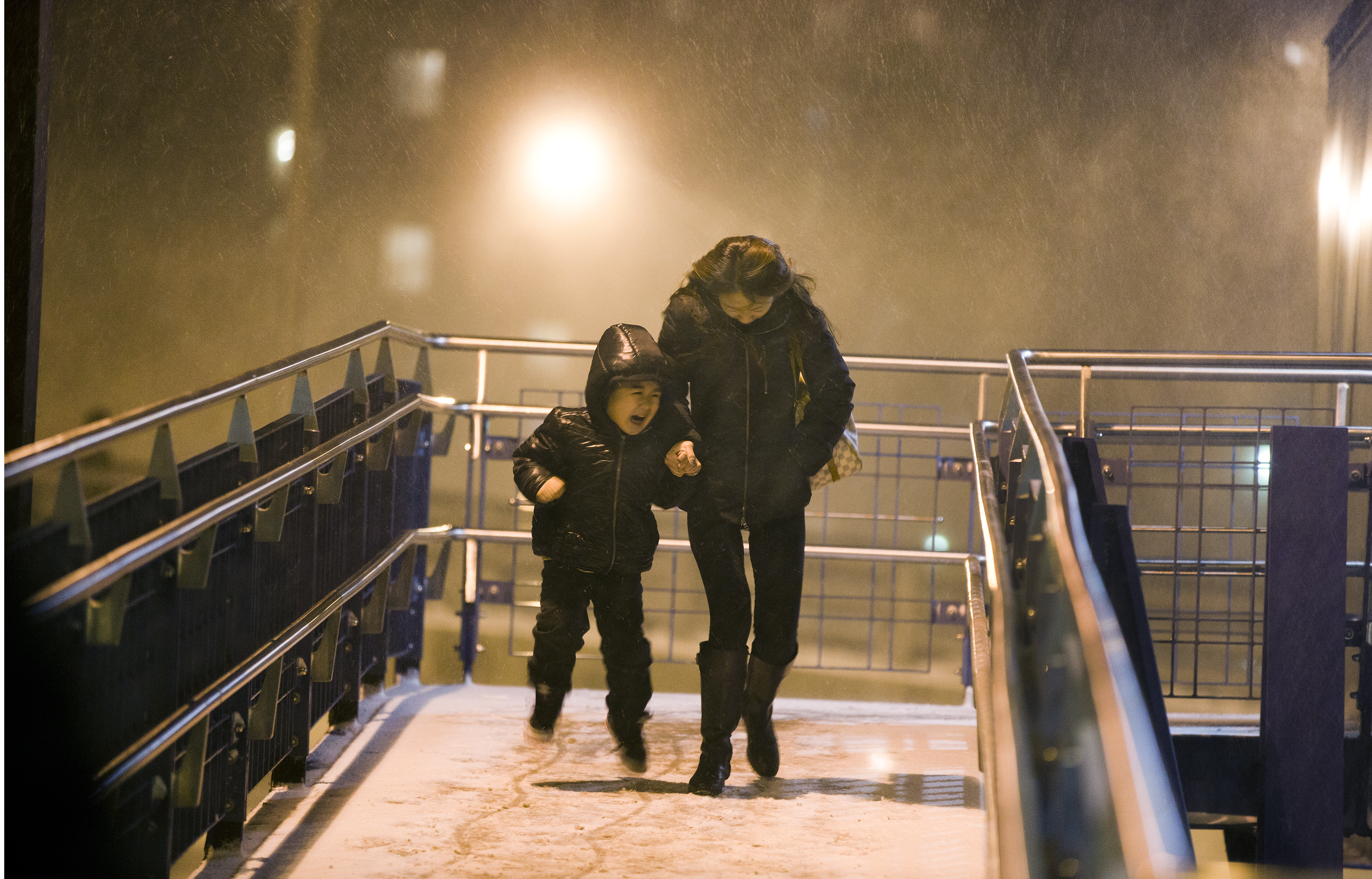 As the storm intensified, a woman and child battled with the wind at the North Quincy MBTA station.