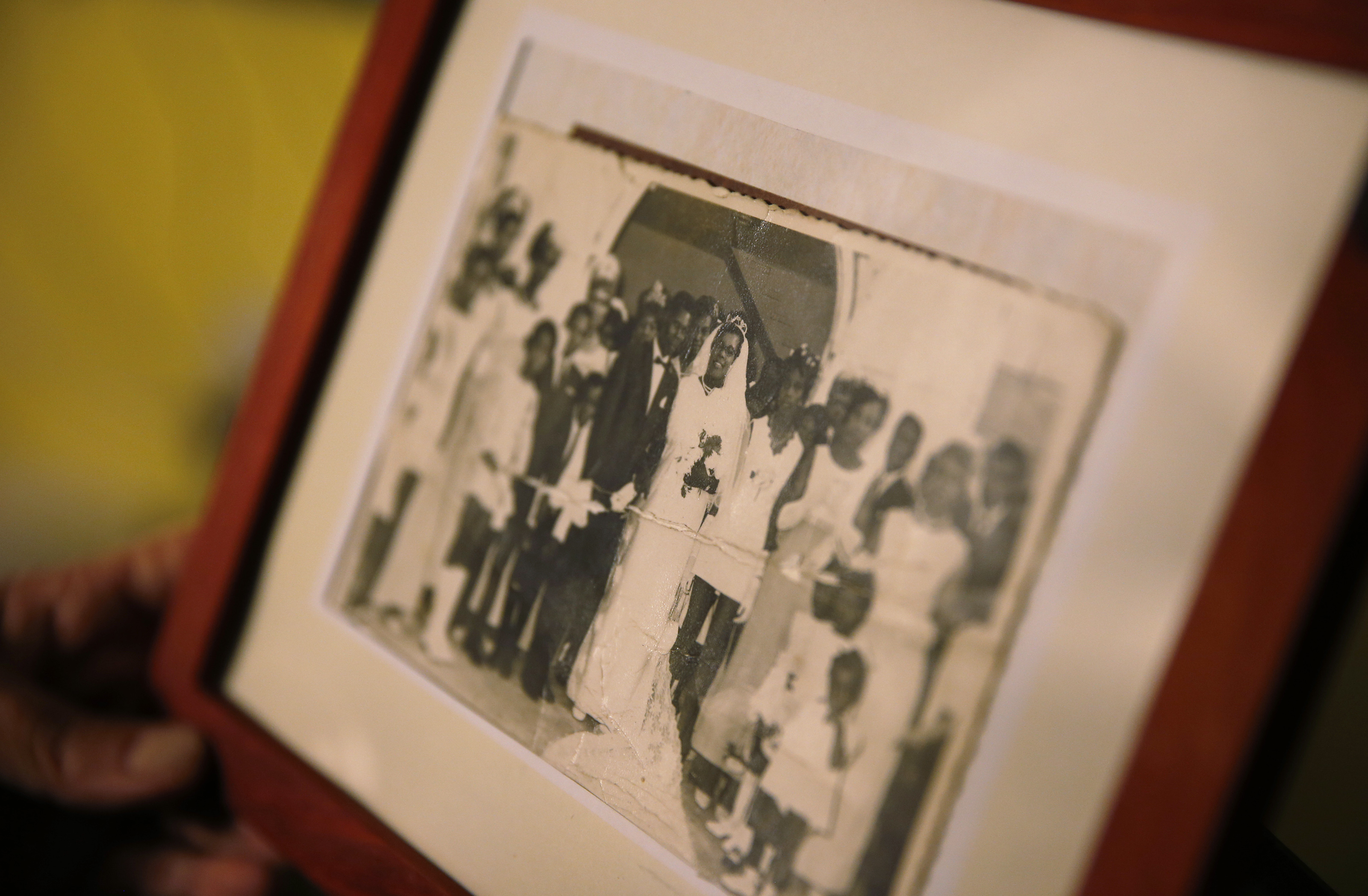 Marcelle Harrison holds a photo of her mother's wedding to her stepfather in Barbados that she keeps on display in the living room of her Cambridge home.