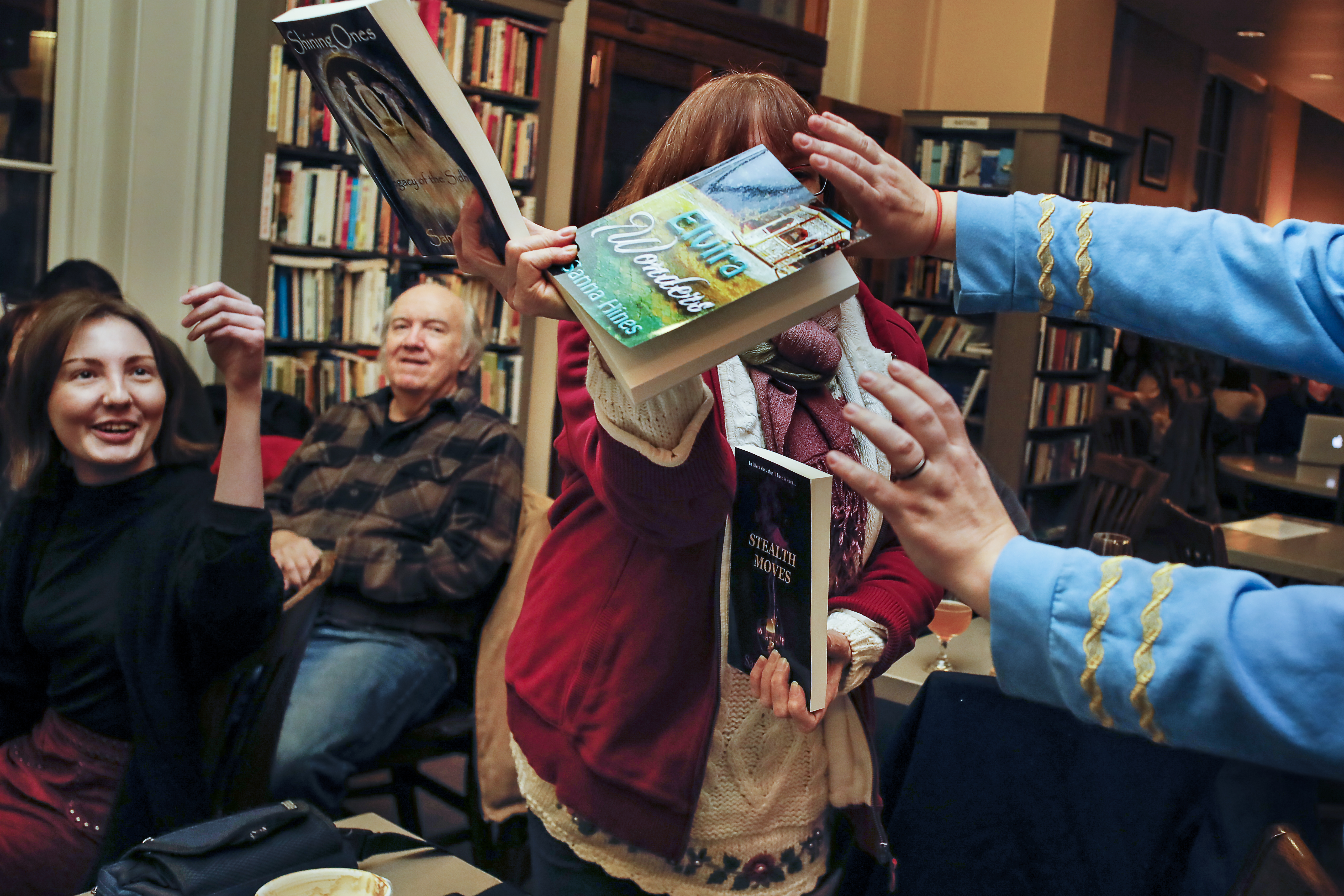 Author Sanna Hines of Maine (center) got help holding up her books to get feedback on the cover art at the Book and Bar "Writers Night Out'' event in Portsmouth, NH.