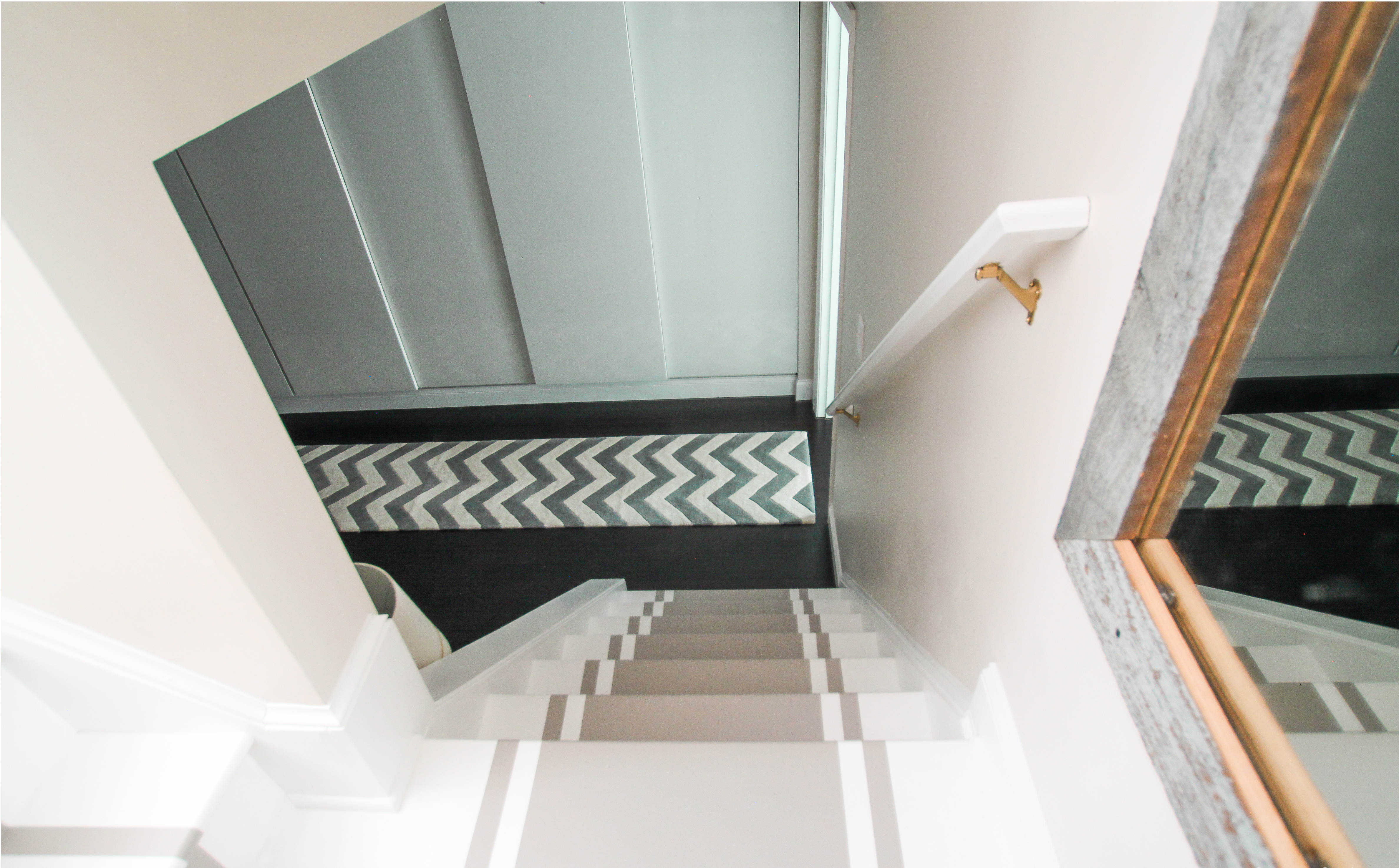 <b>AFTER</b> The owners covered the steps with a glossy white paint, then used painter’s tape to mark off a runner, which was finished in a gray shade.