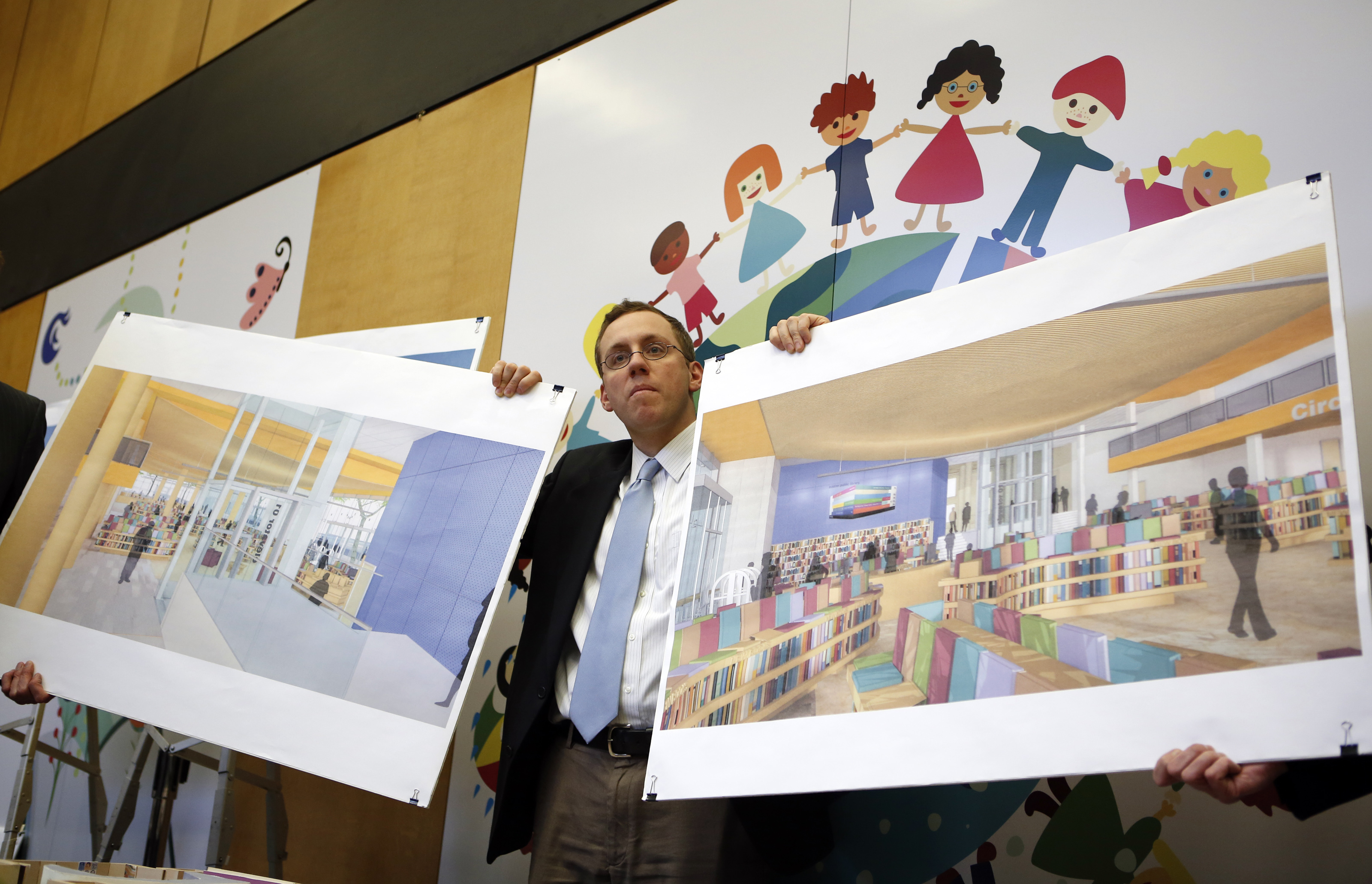 Architect Andy Jonic holds artists’ renderings showing the BPL group the planned renovation of the children’s room and addition of a teen center.