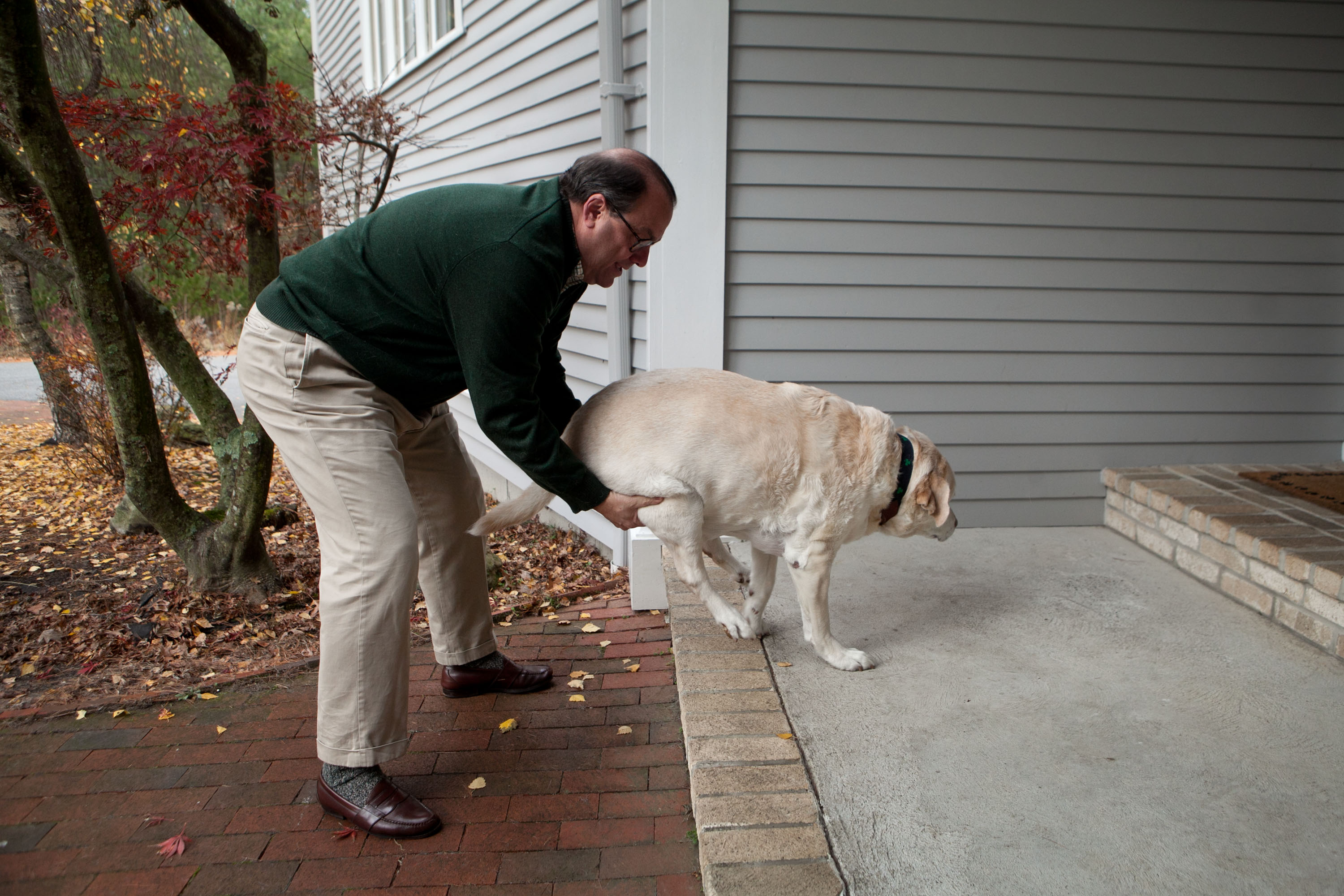 Kevan Cunningham helps Dempsey, who can no longer climb stairs, back into the house.