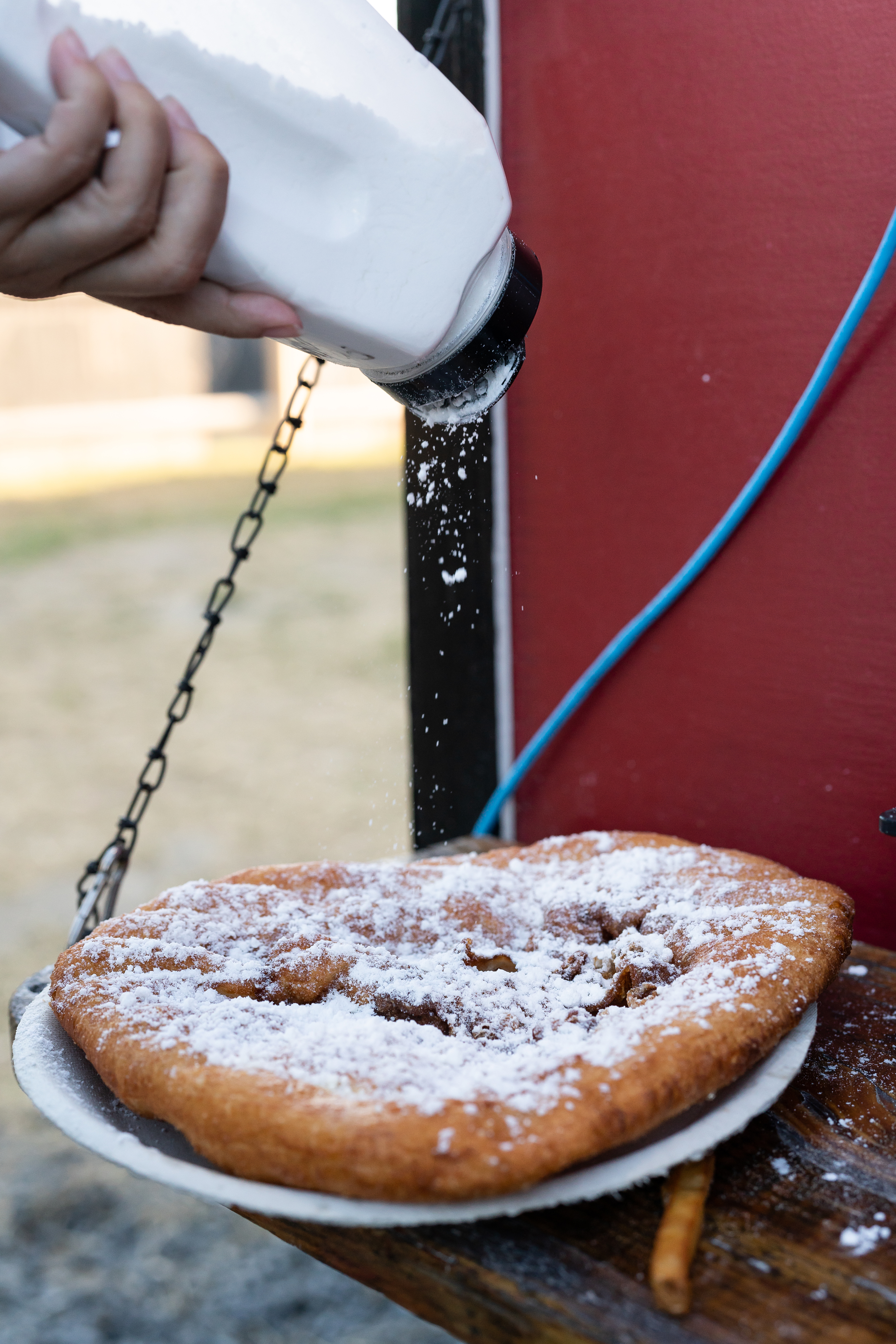 A patron puts powdered sugar on fried dough from Big Grampa's Grill food truck at Congdon's After Dark.