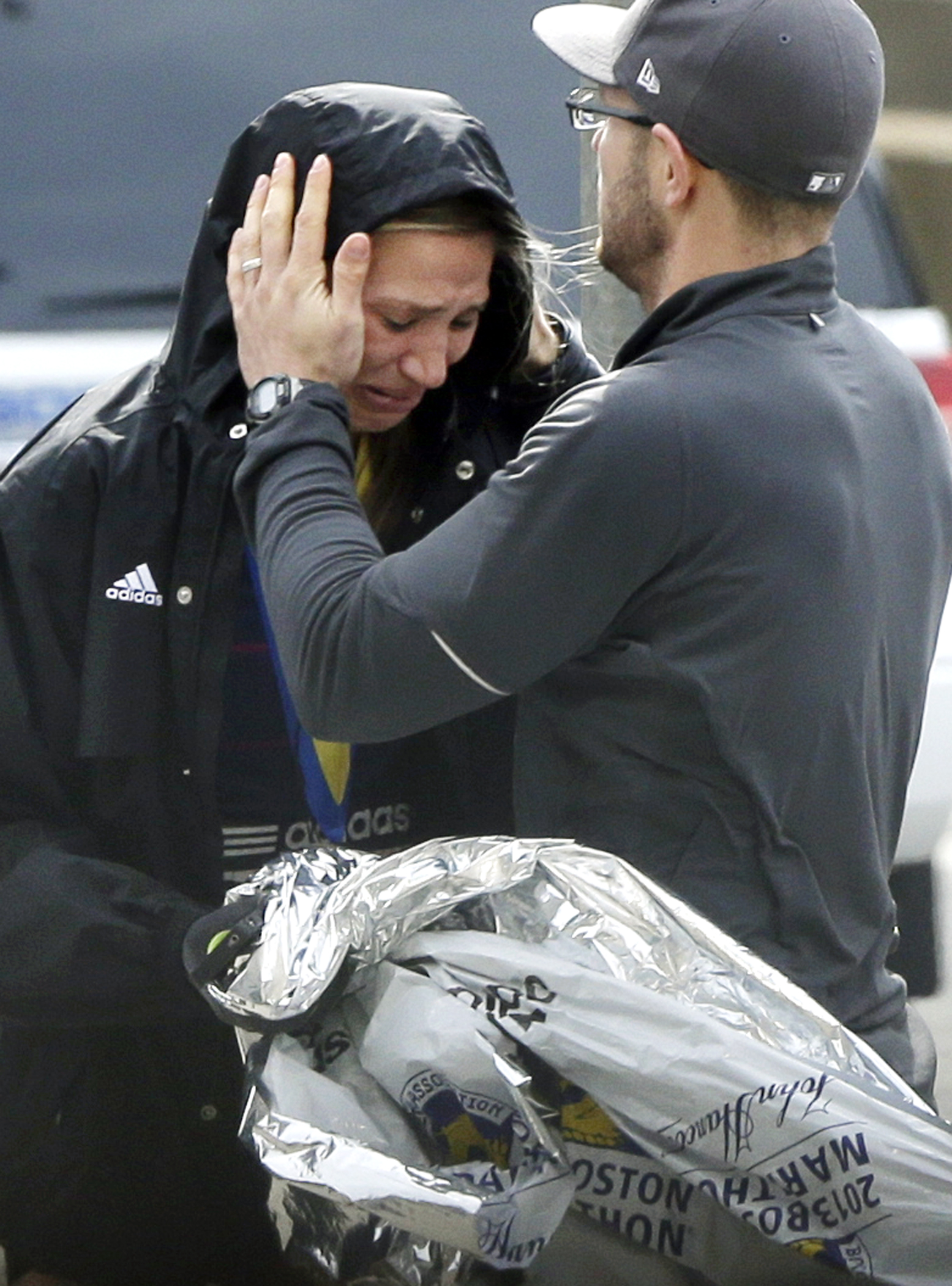 An unidentified Boston Marathon runner was comforted as she cried in the aftermath of the bombing.