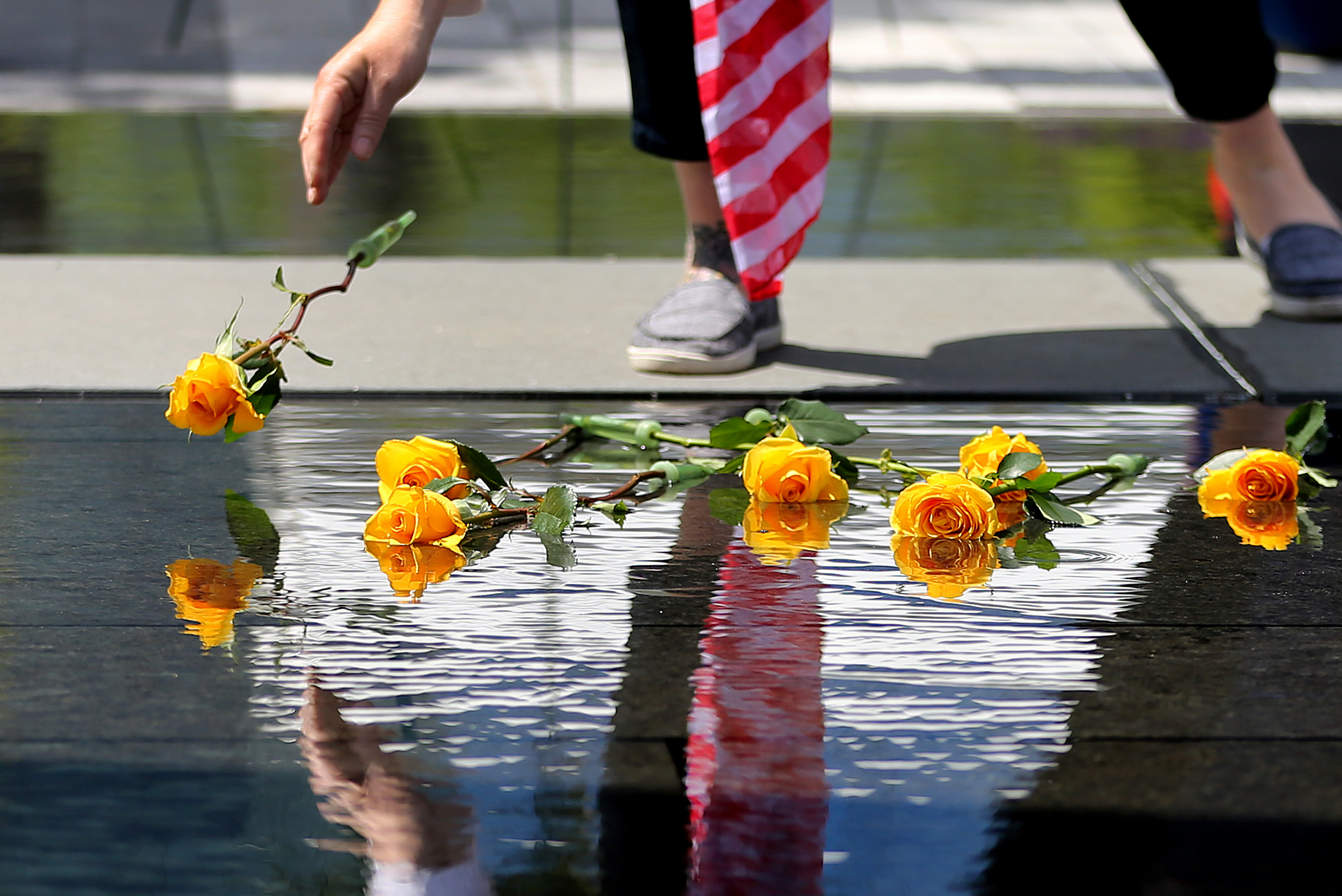 A Gold Star family member placed a yellow rose into the water of the Massachusetts Fallen Heroes Memorial during a re-dedication ceremony on Saturday.