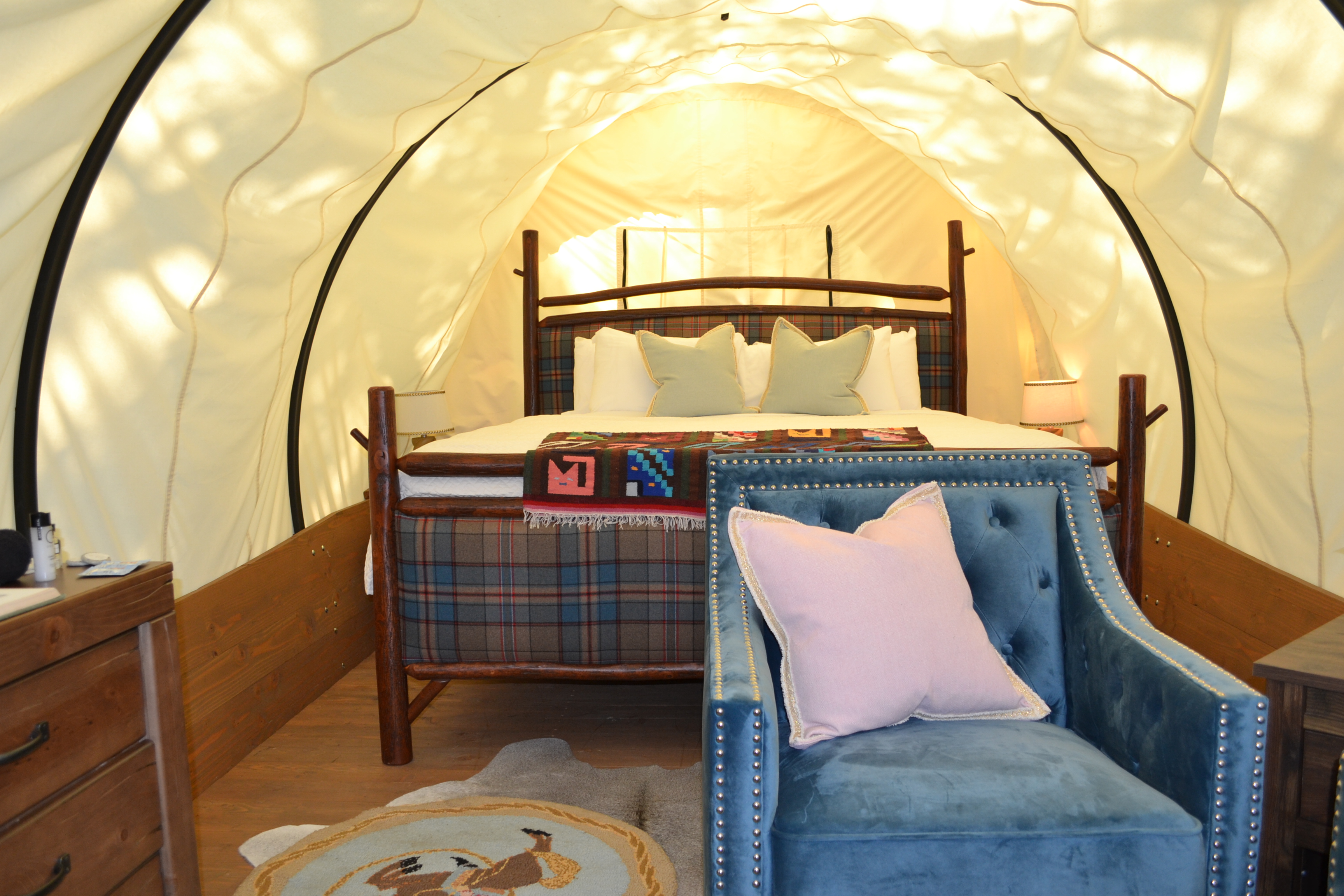 Inside one of the Conestoga wagons at Sandy Pines Campground is a comfy bed and nice furnishings.