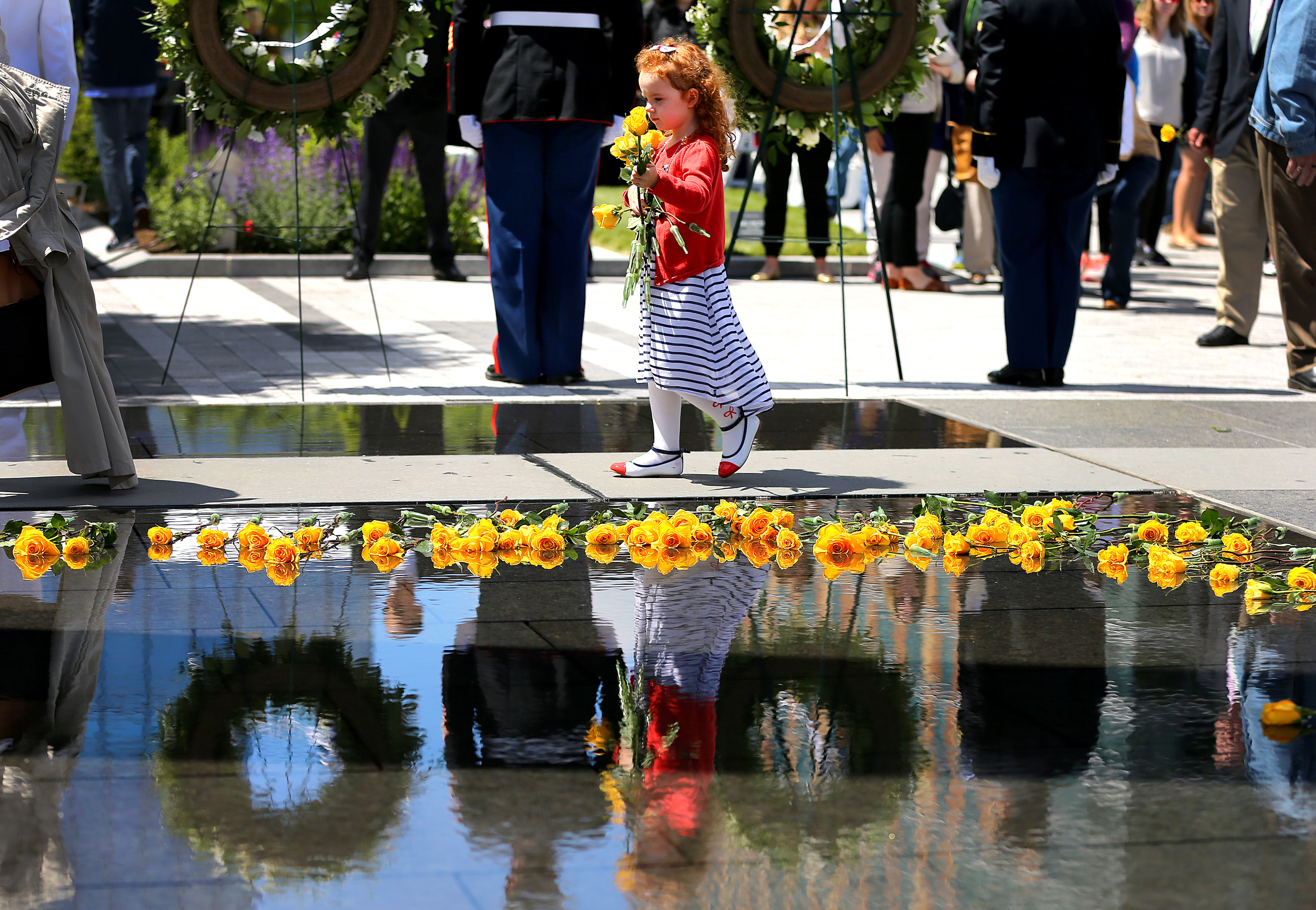 Brooklynn Eggers, 4 from Londonderry, N.H., carried yellow roses to place into the water of the Massachusetts Fallen Heroes Memorial during a re-dedication ceremony held at the site on Northern Avenue.